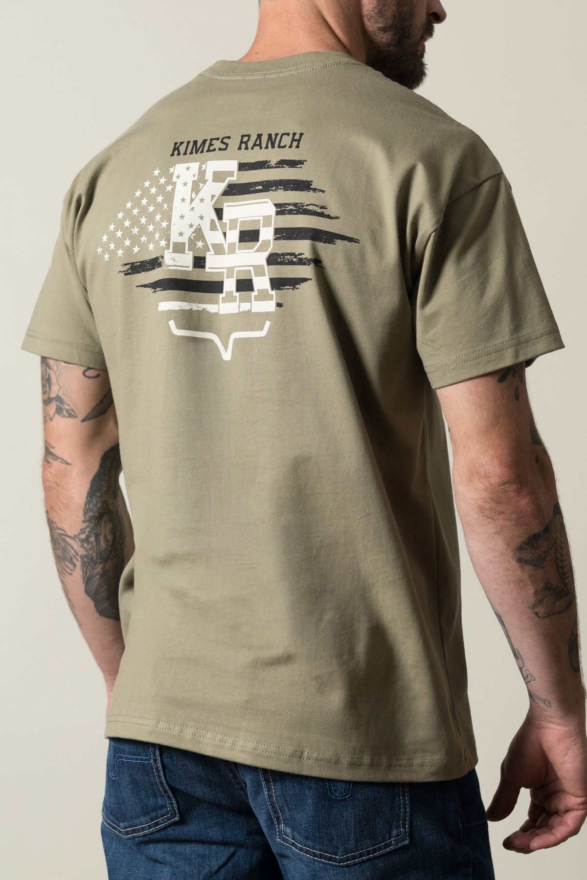Kimes Ranch Red Glare short-sleeve shirt, Light Olive, featuring a back graphic with Kimes Ranch text, stars, and stripes