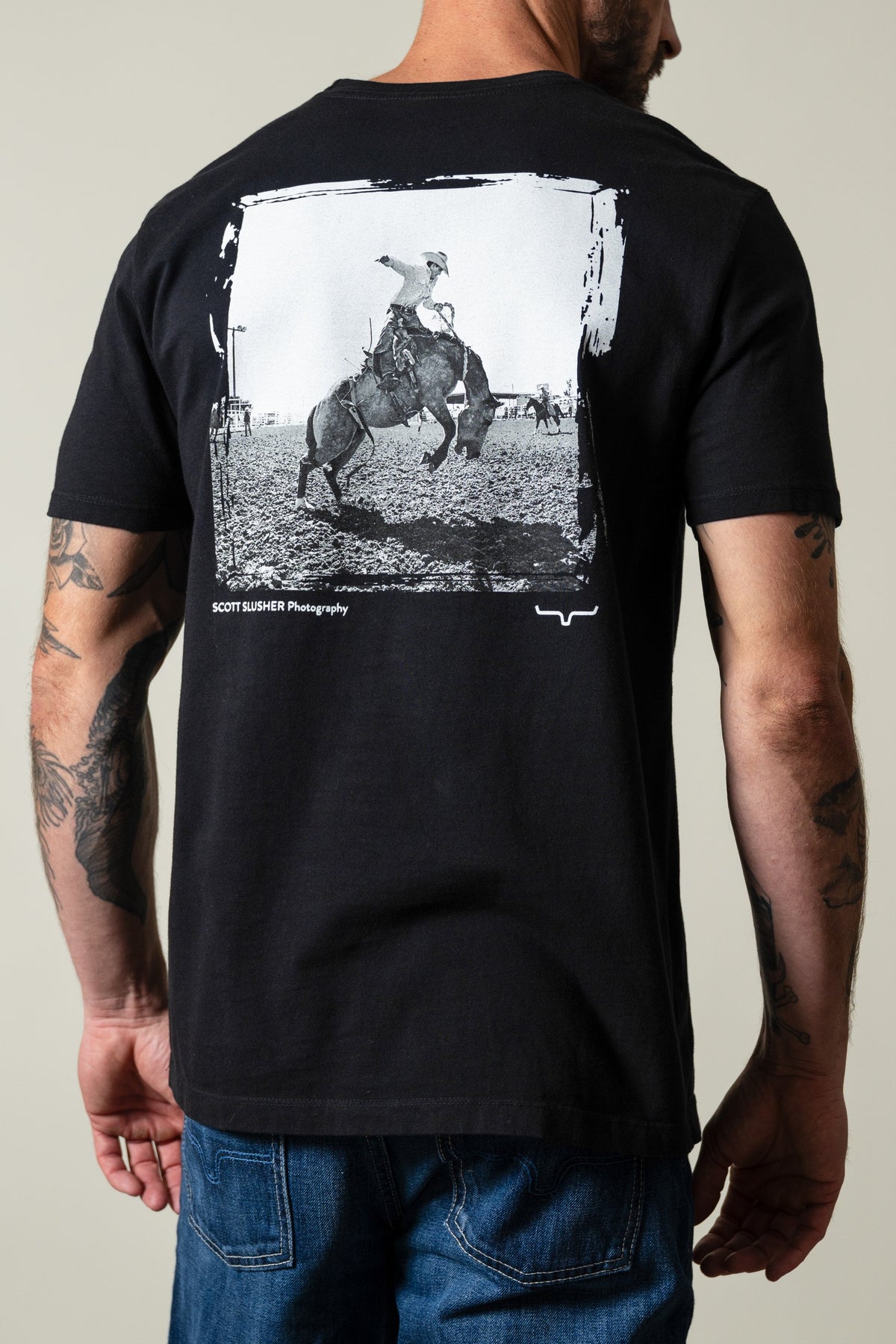 Kimes Ranch SS Bronc Ride shirt, black, back view showing cowboy bucking bronc graphic with SCOTT SLUSHER Photography text