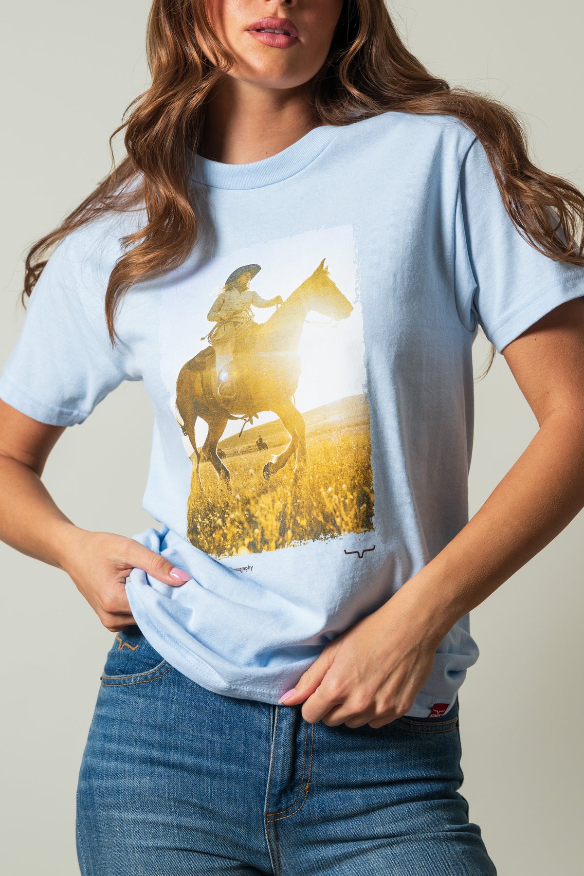 Kimes Ranch SS Riding Sunshine powder blue shirt with a graphic of a rider on a horse in a sunny field