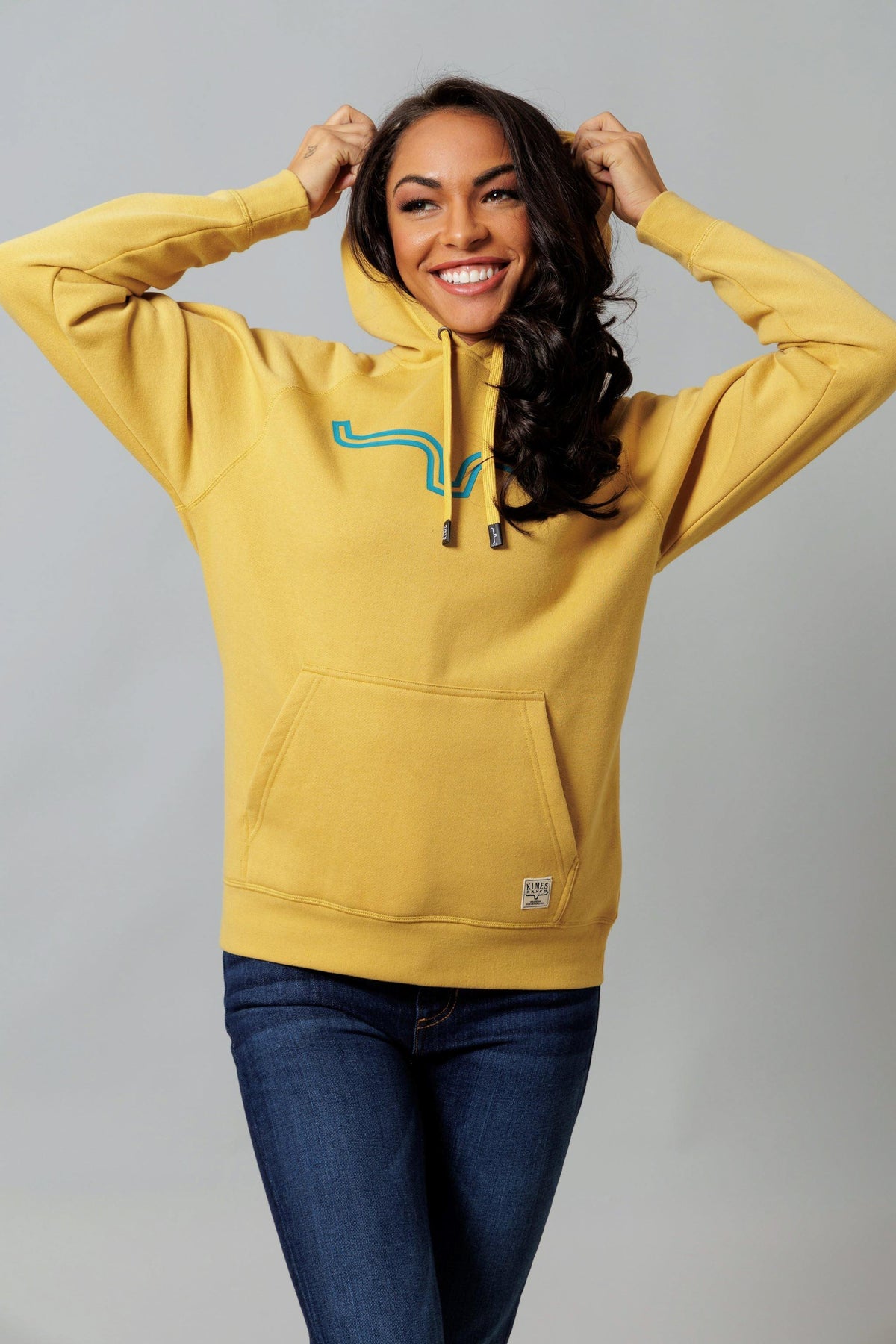 Kimes Ranch Ladies Outlier Hoodie in Gold with a blue graphic and kangaroo pocket