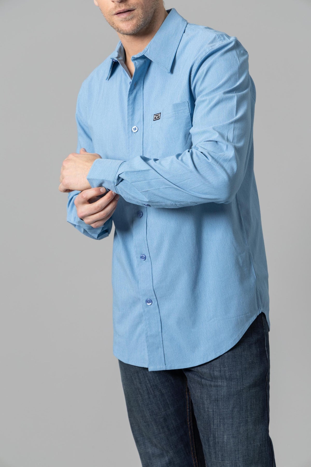Kimes Ranch Linville Long Sleeve Dress Shirt in Mid Blue, side view, with a chest pocket and logo