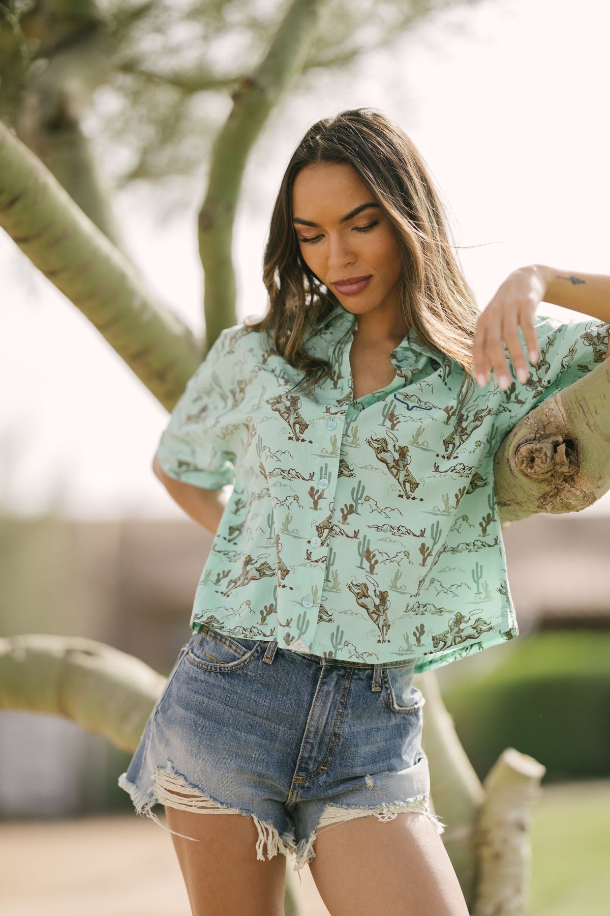 Kimes Ranch Ranchero top in Turquoise with a western print of cowboys and cacti