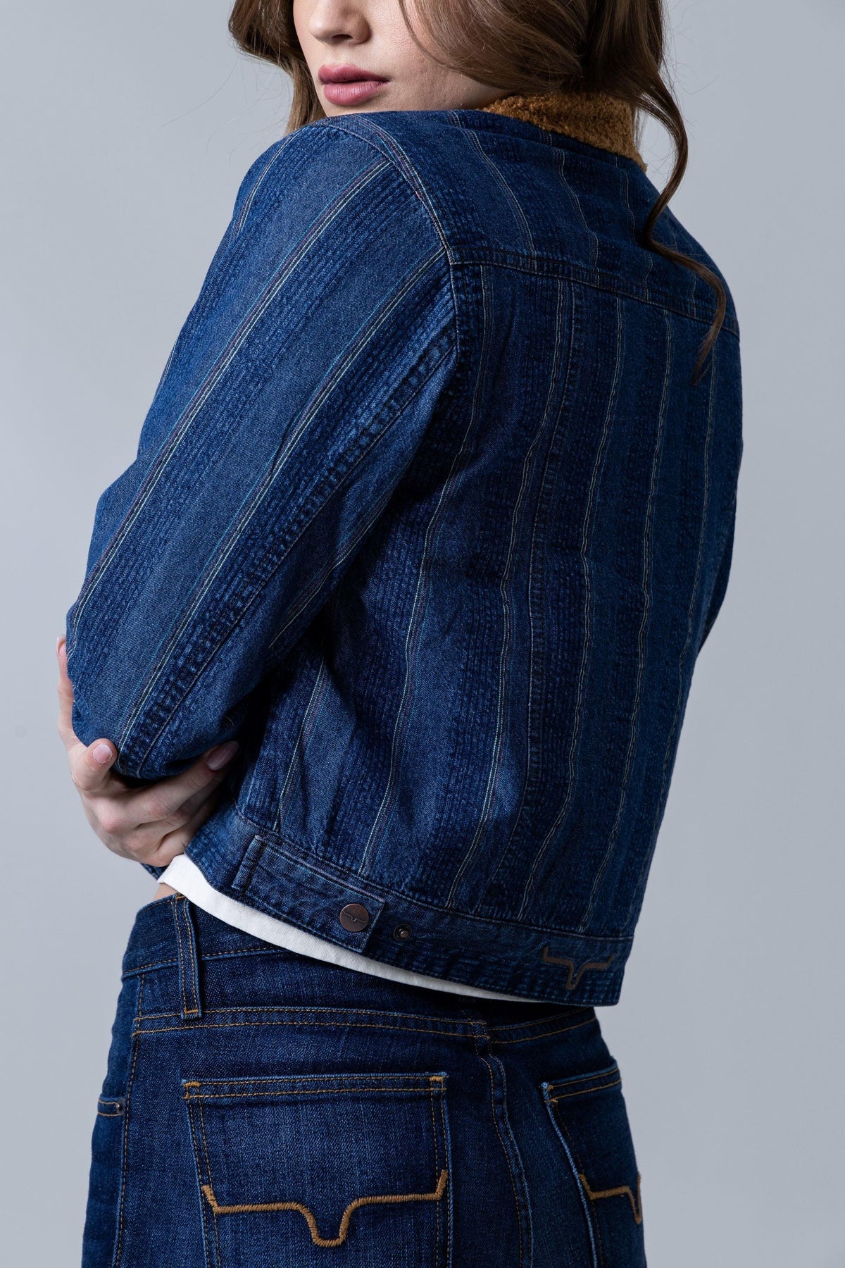 Kimes Ranch Vaquero Trucker jacket in Dark Indigo, side view, with contrast stitching and a Kimes Ranch logo at the hem