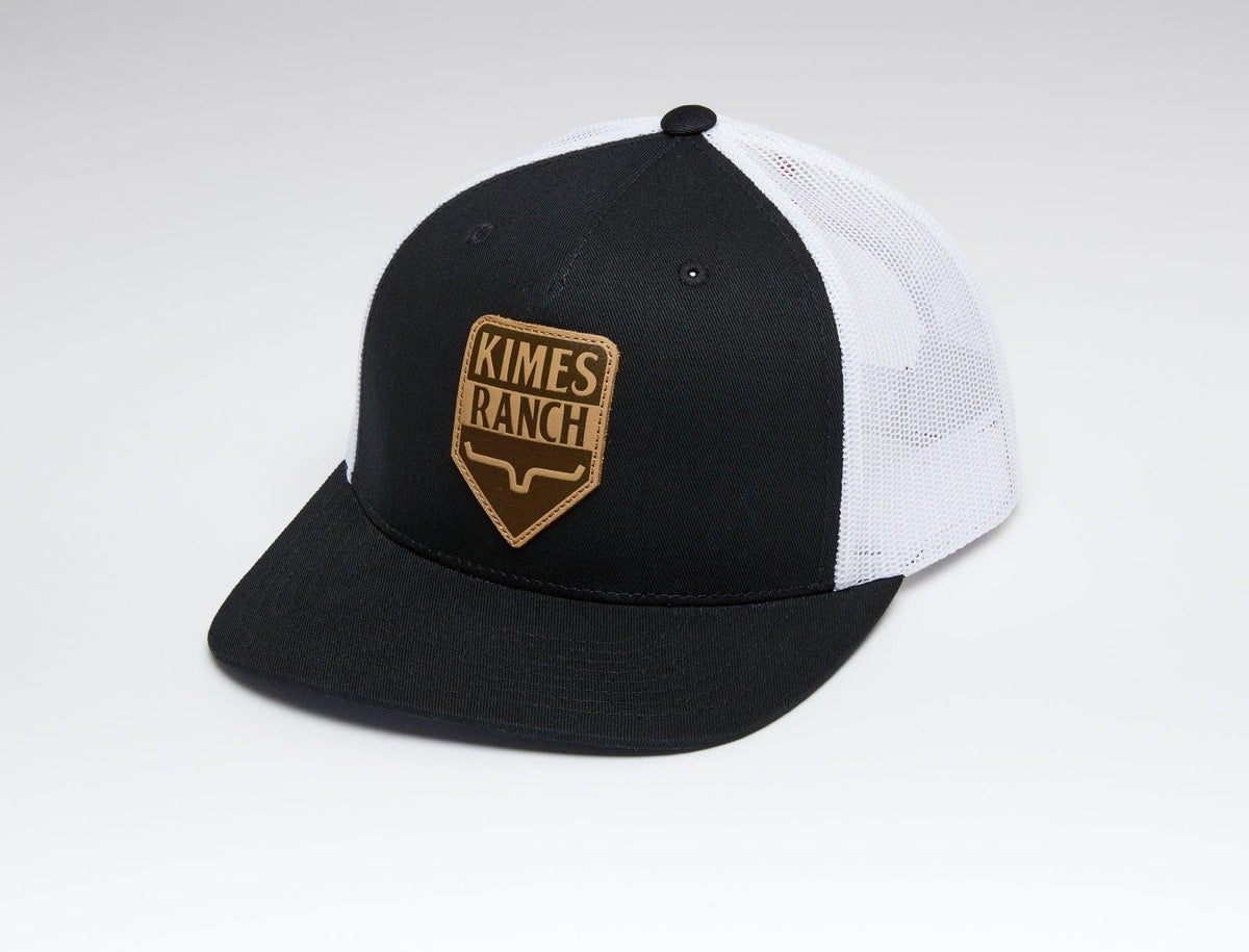 Kimes Ranch Drop In Trucker Hat in Black with a front logo patch and white mesh back