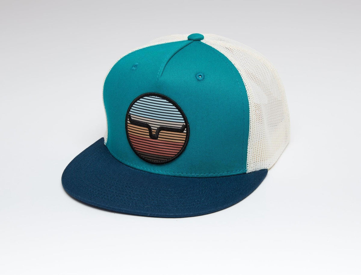Kimes Ranch The Graduate Trucker Hat in Teal, side view, with a navy brim and a retro sunset patch