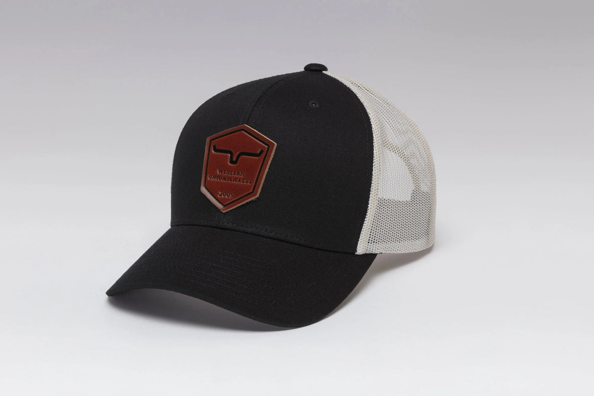 Kimes Ranch Shielded Trucker Hat in Black, side view, with a brown shield patch reading Western Uncomplicated 2009