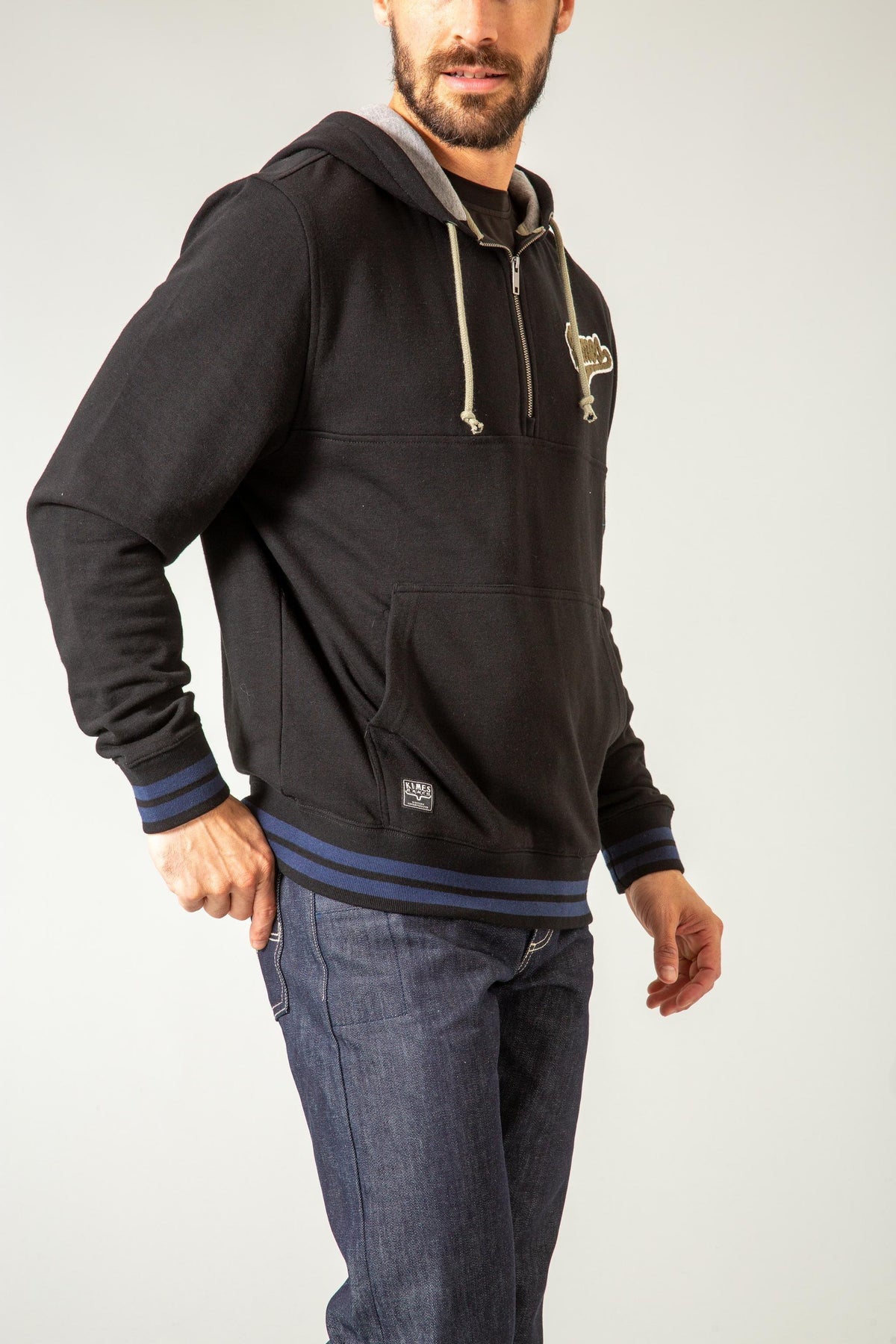 Kimes Ranch Team One Hoodie in Black, side view, with a half zip, kangaroo pocket, and blue striped cuffs