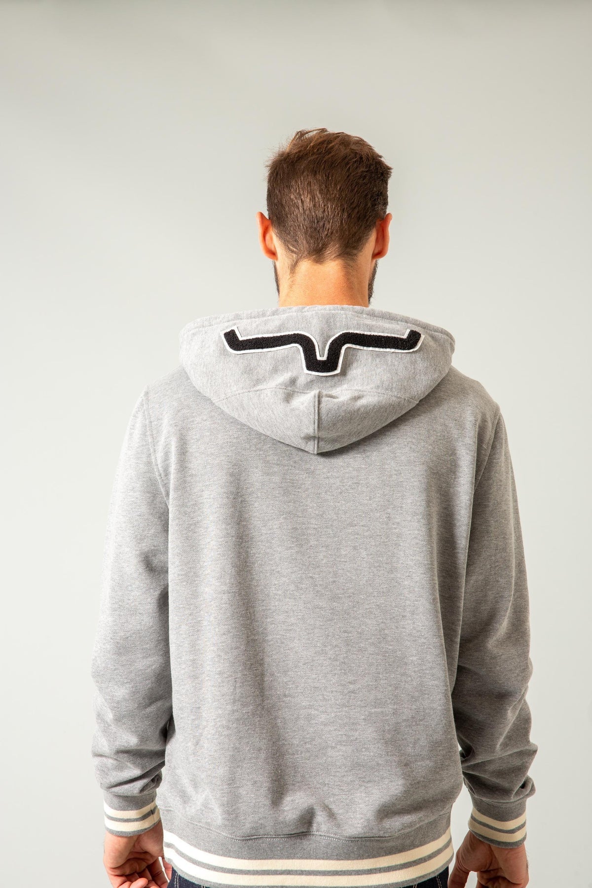 Kimes Ranch Team One Hoodie in Grey Heather, back view, with a black and white logo on the hood back and striped cuffs