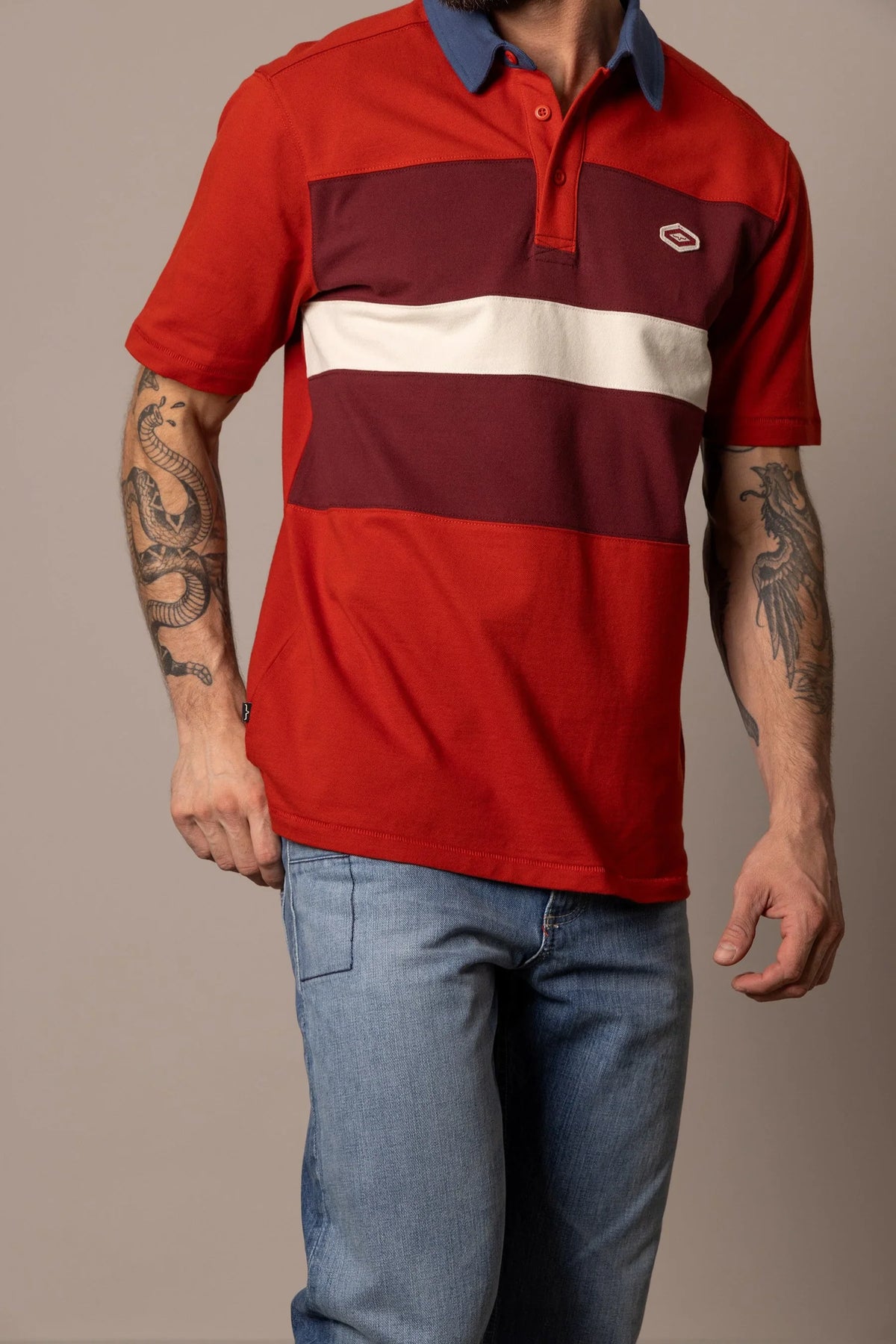 Kimes Ranch 1874 Polo in Brick Red with a blue collar and horizontal stripes in burgundy and cream