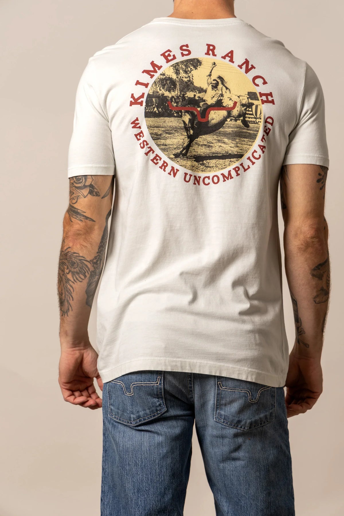 Kimes Ranch 1956 shirt in Natural, back view, with a back graphic of a cowboy on a bucking horse