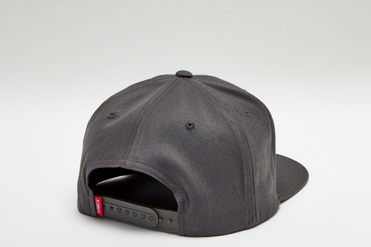 Kimes Ranch Arched Trucker Hat in Charcoal, back view, with the adjustable snap closure and red Kimes Ranch logo tag