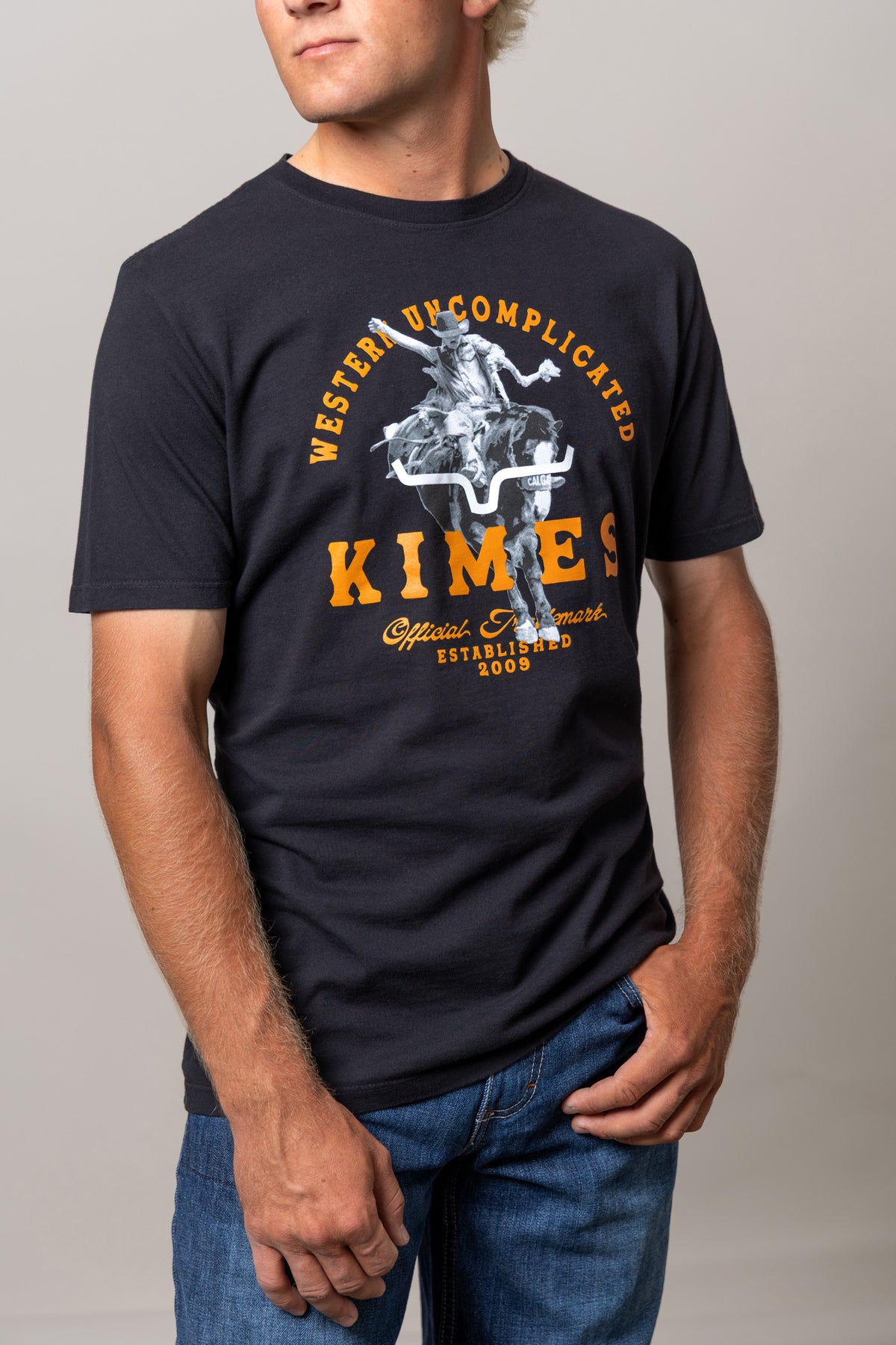 Kimes Ranch Break Through shirt with a graphic of a cowboy riding a longhorn with text reading Western Uncomplicated Kimes