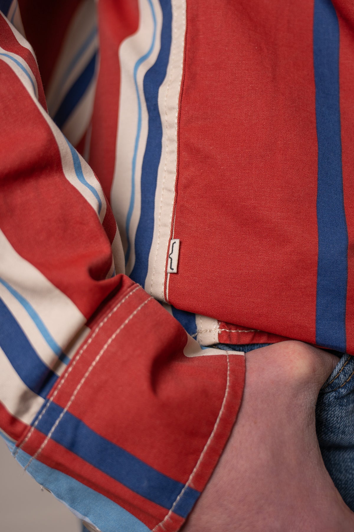 Kimes Ranch Clancy dress shirt in Brick Red with blue and white stripes and a close-up of the sleeve cuff