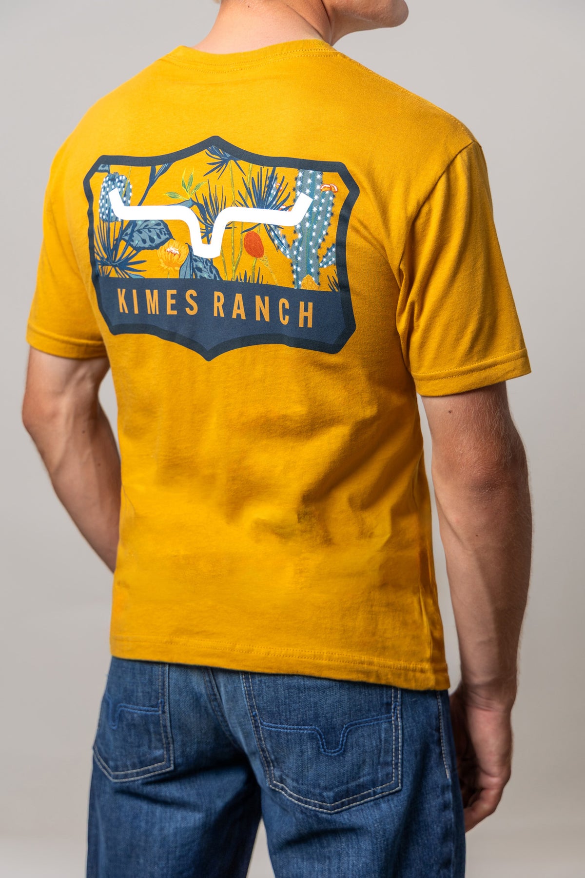 Kimes Ranch Dillard Floral shirt in Antique Gold, back view, with a back graphic of cacti and the Kimes Ranch logo