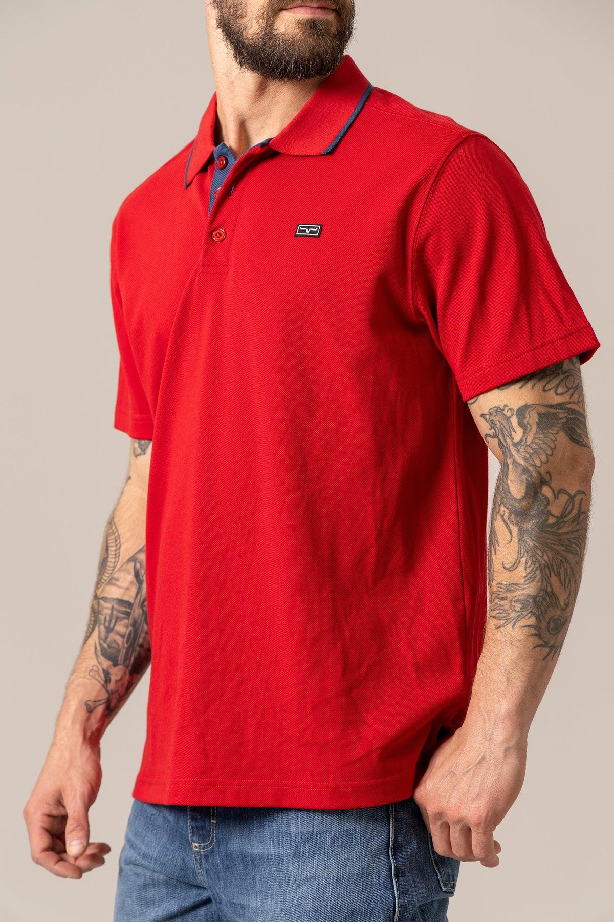 Kimes Ranch El Capitan Polo in Red, side view, with navy collar trim and a small logo on the chest