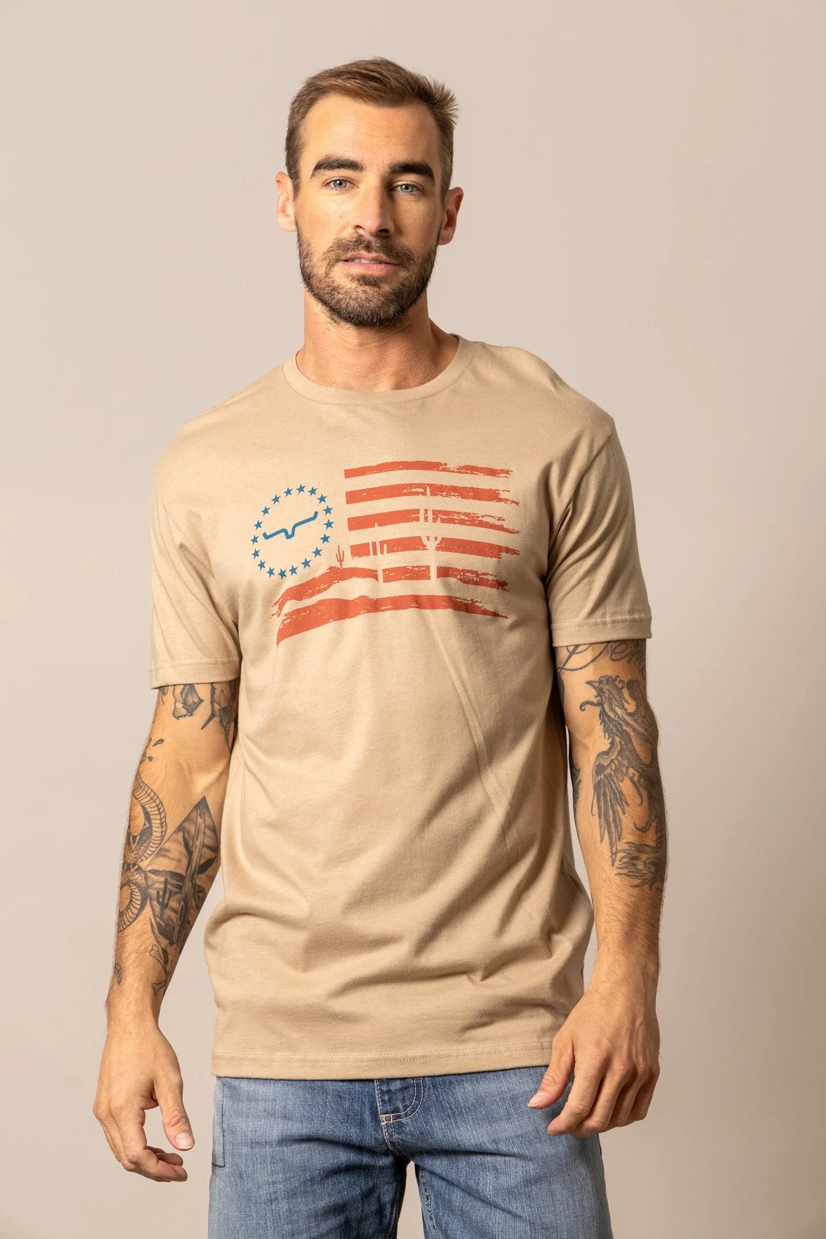Kimes Ranch Faded Tan short sleeve shirt with a distressed American flag graphic featuring the Kimes Ranch logo and cactus