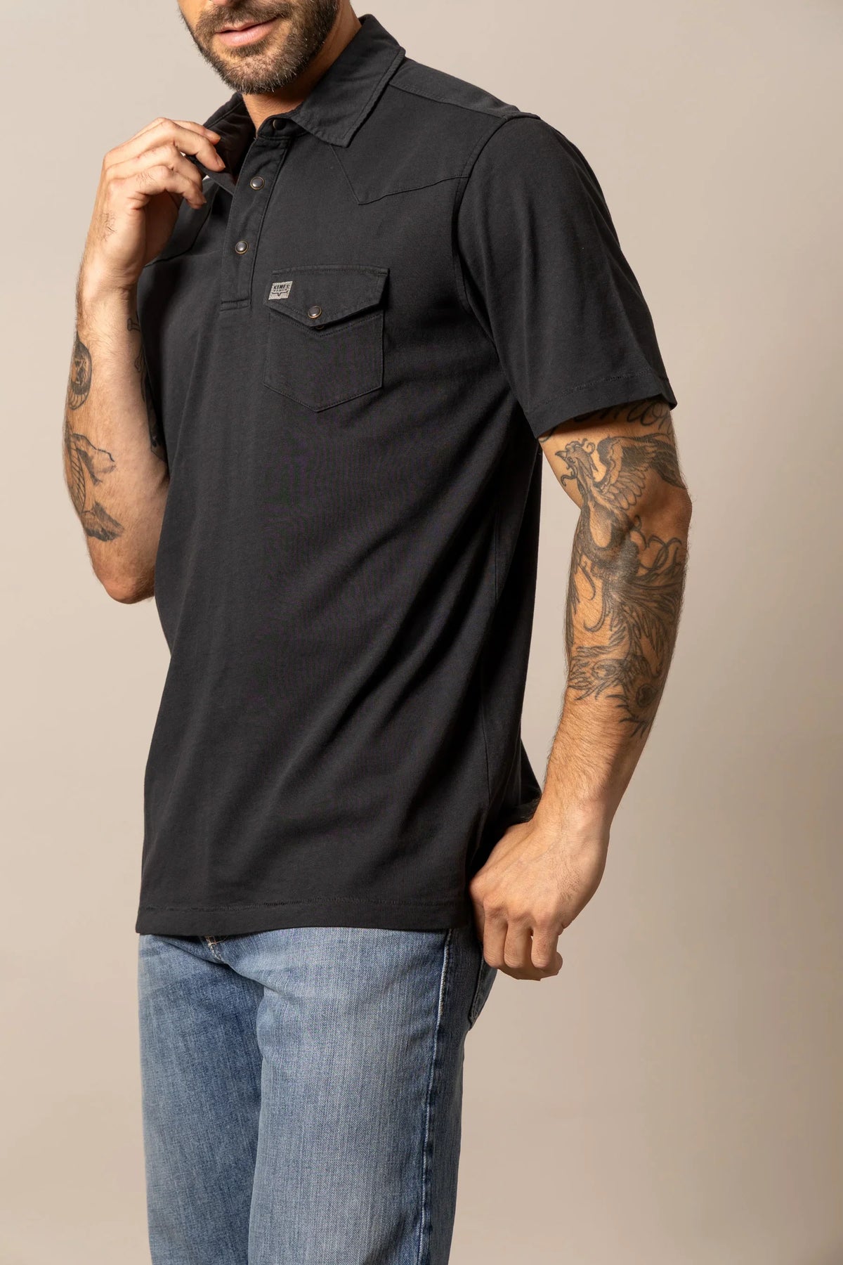 Kimes Ranch Fluger Polo in Black, side view, with a chest pocket and logo patch