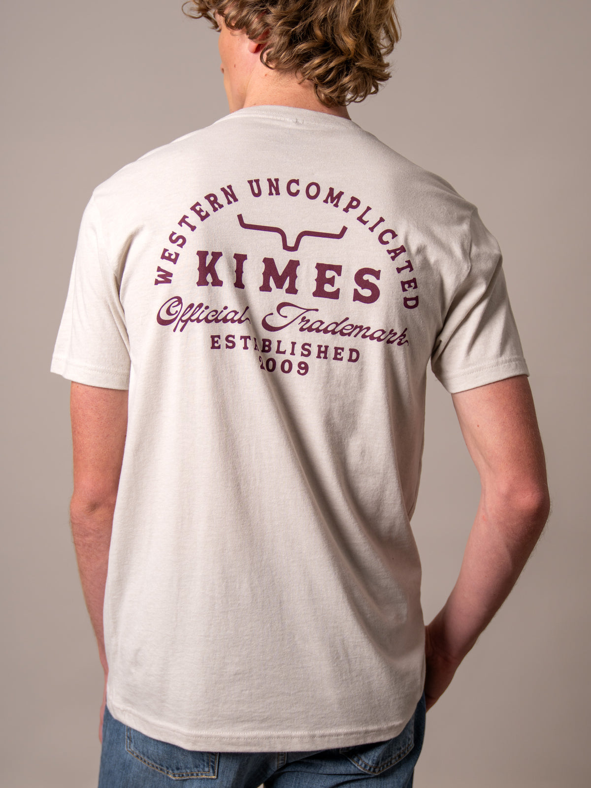 Kimes Ranch Heavy Text shirt in Natural, back view, with back graphic reading Western Uncomplicated Kimes Official Trademark