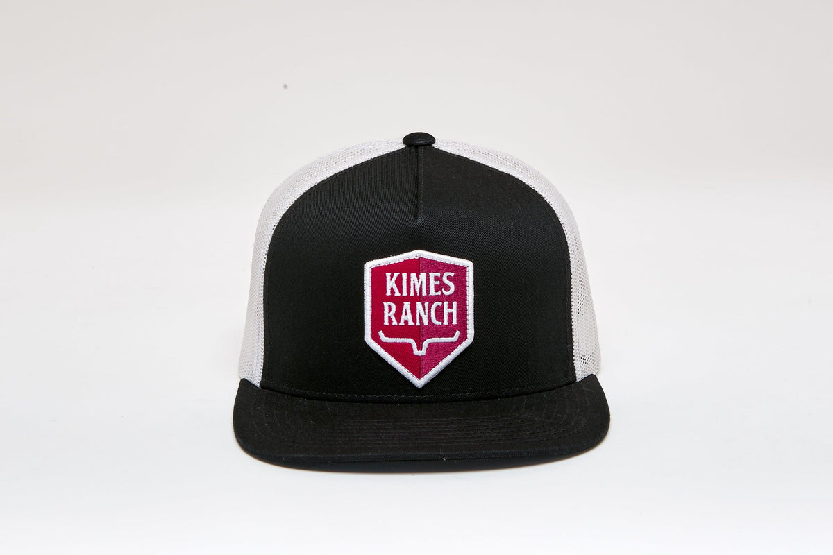 Kimes Ranch Jack Trucker Hat in Black with a red and white shield logo on the front