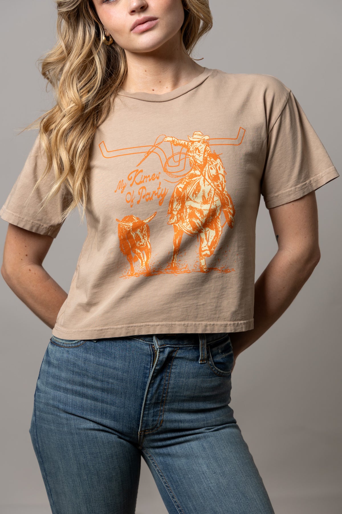 Kimes Of A Party shirt in Tan with a graphic of a cowboy on a bucking horse and a steer with the text My Kimes Of Party
