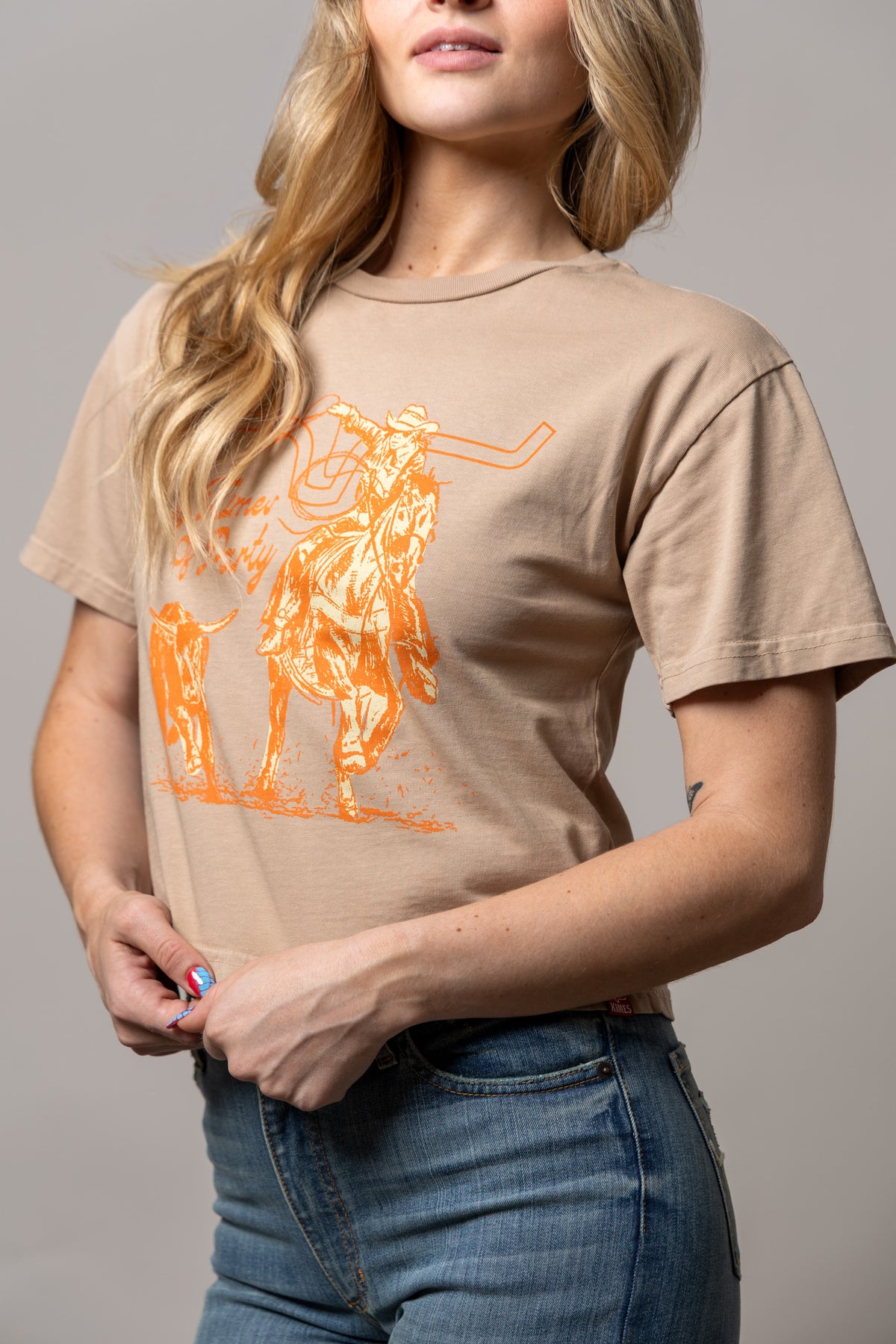 Kimes Of A Party shirt in Tan with a graphic of a cowboy on a bucking horse and a steer with the text Times of Party