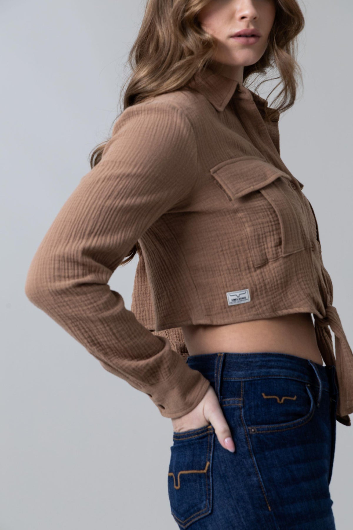 Kimes Ranch Torrean Tie Up top in Taupe, side view, with long sleeves, a collar, front pockets and a side tie detail