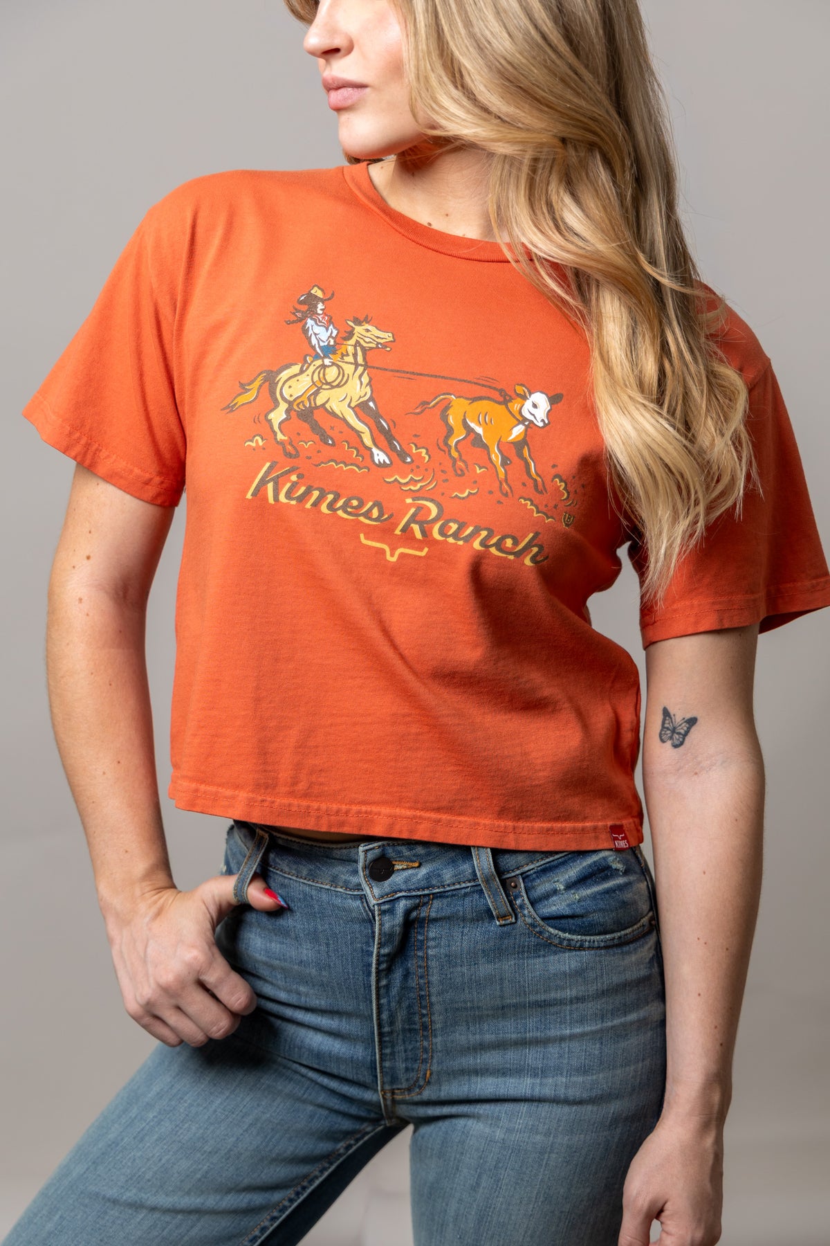 Kimes Ranch Lucky B Roper shirt in Spice Red with a graphic of a cowgirl roping a calf and the Kimes Ranch logo