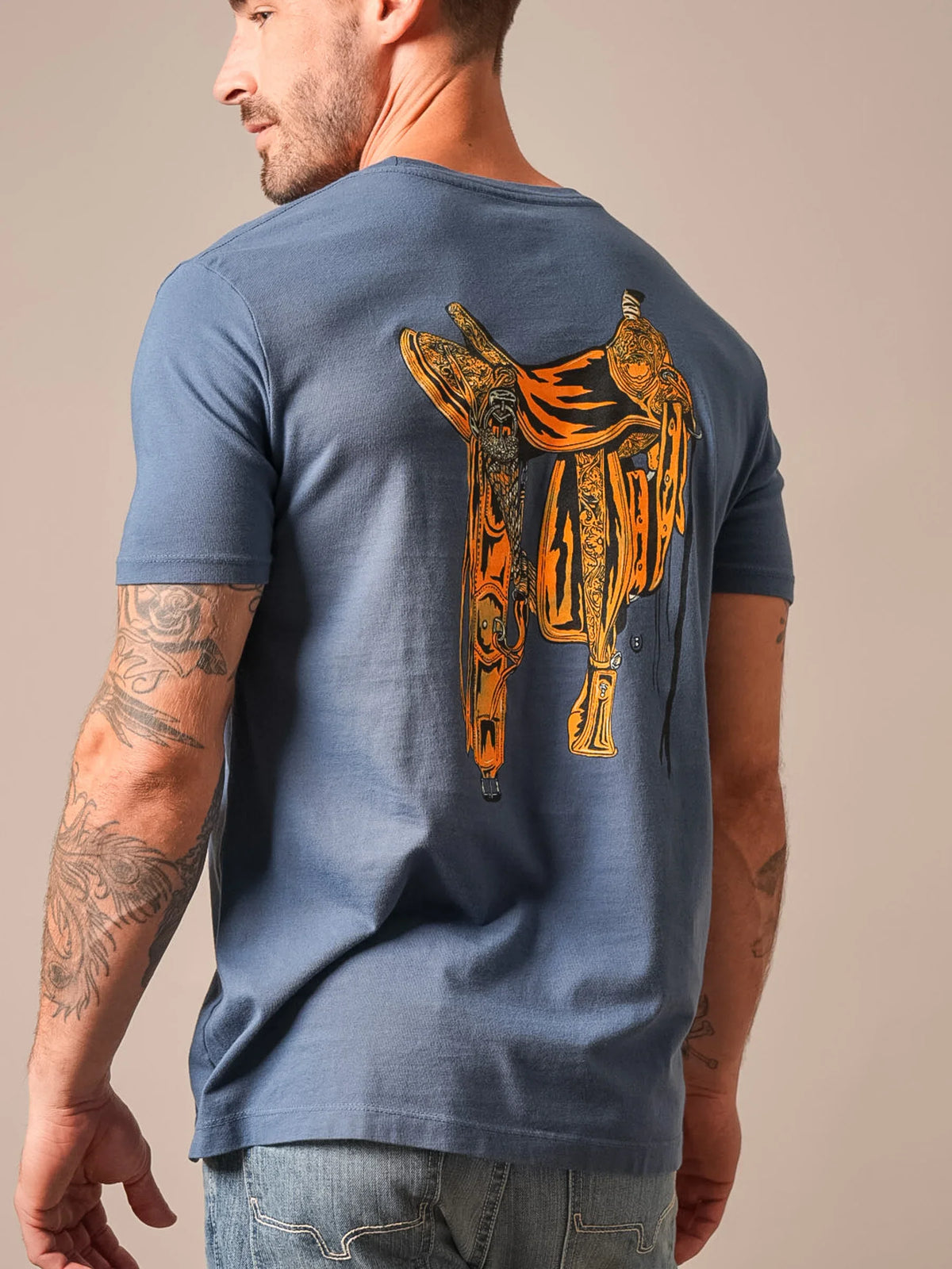 Kimes Ranch Lucky B Saddle shirt in Dark Blue, back view, with a large orange and black saddle graphic on the back