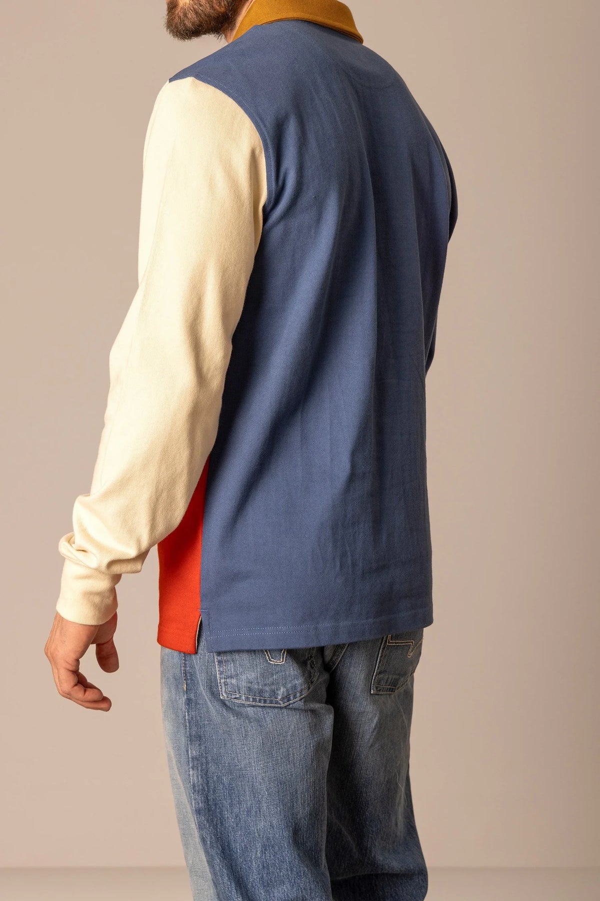Kimes Ranch Marx Rugby polo in Dark Blue, side view, with cream sleeves and orange side panel