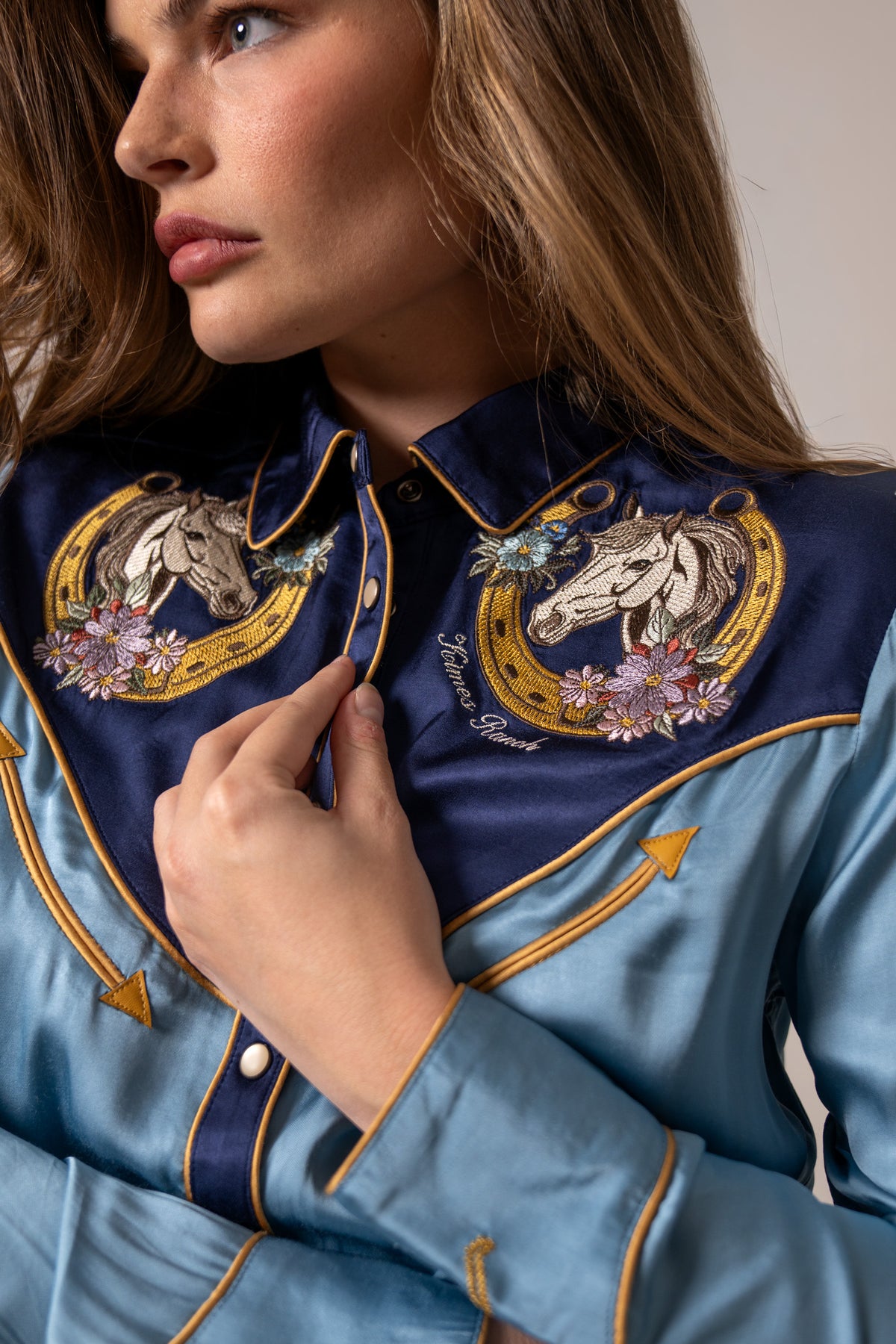 Kimes Ranch Merada, close-up, top with embroidered horseshoe and horse head yoke with floral accents and gold piping