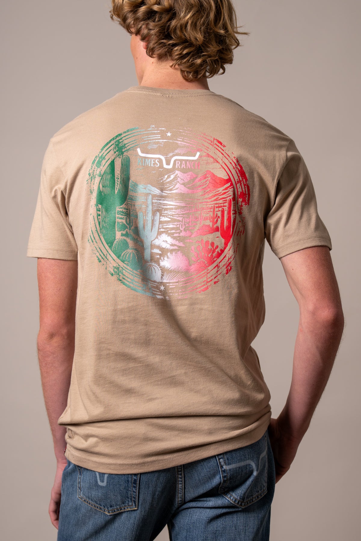 Kimes Ranch Mexico Prairie shirt in Tan, back view, with a back graphic of a desert landscape and the Kimes Ranch logo