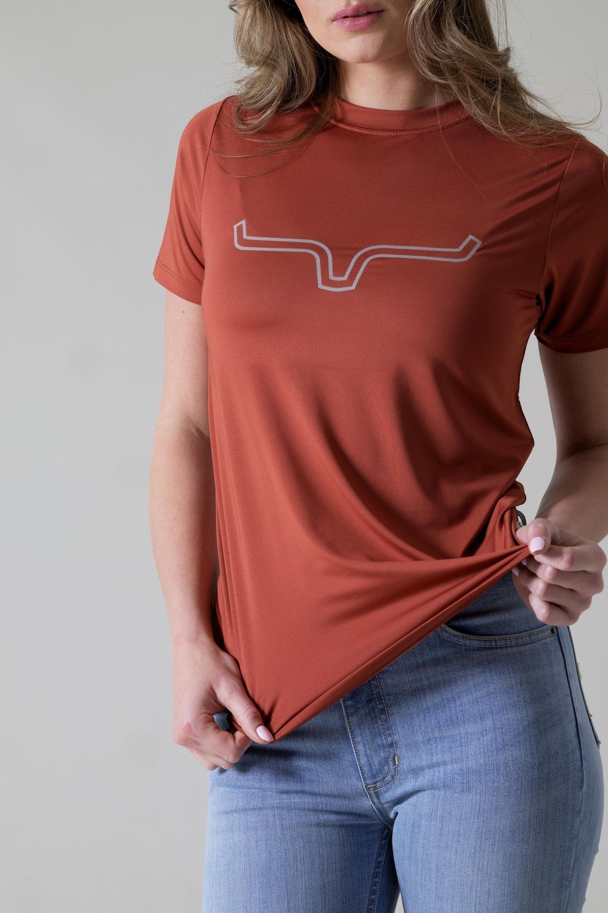 Kimes Ranch Ladies Outlier Tech Tee Shirt in Rust with a white outline logo on the chest