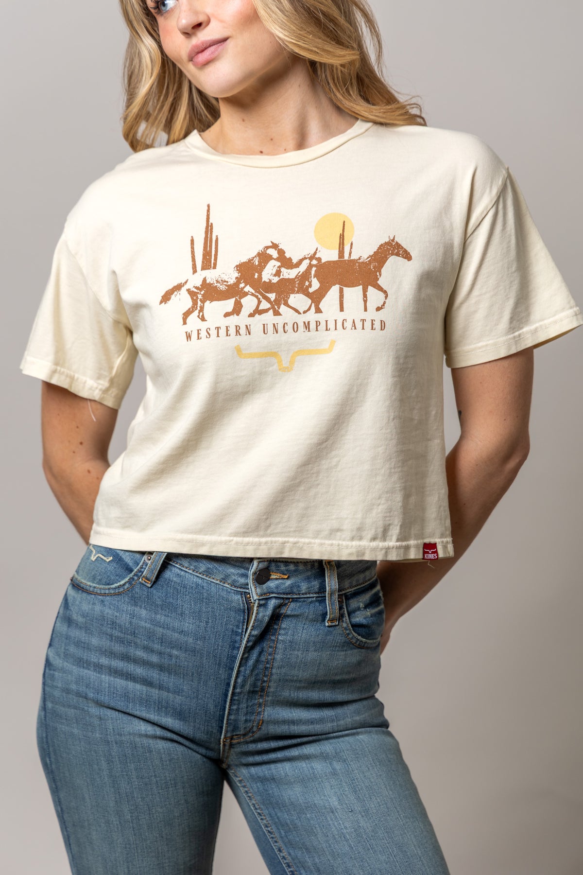 Kimes Ranch Plains Stampede shirt in Ivory with a graphic of running horses and the text Western Uncomplicated