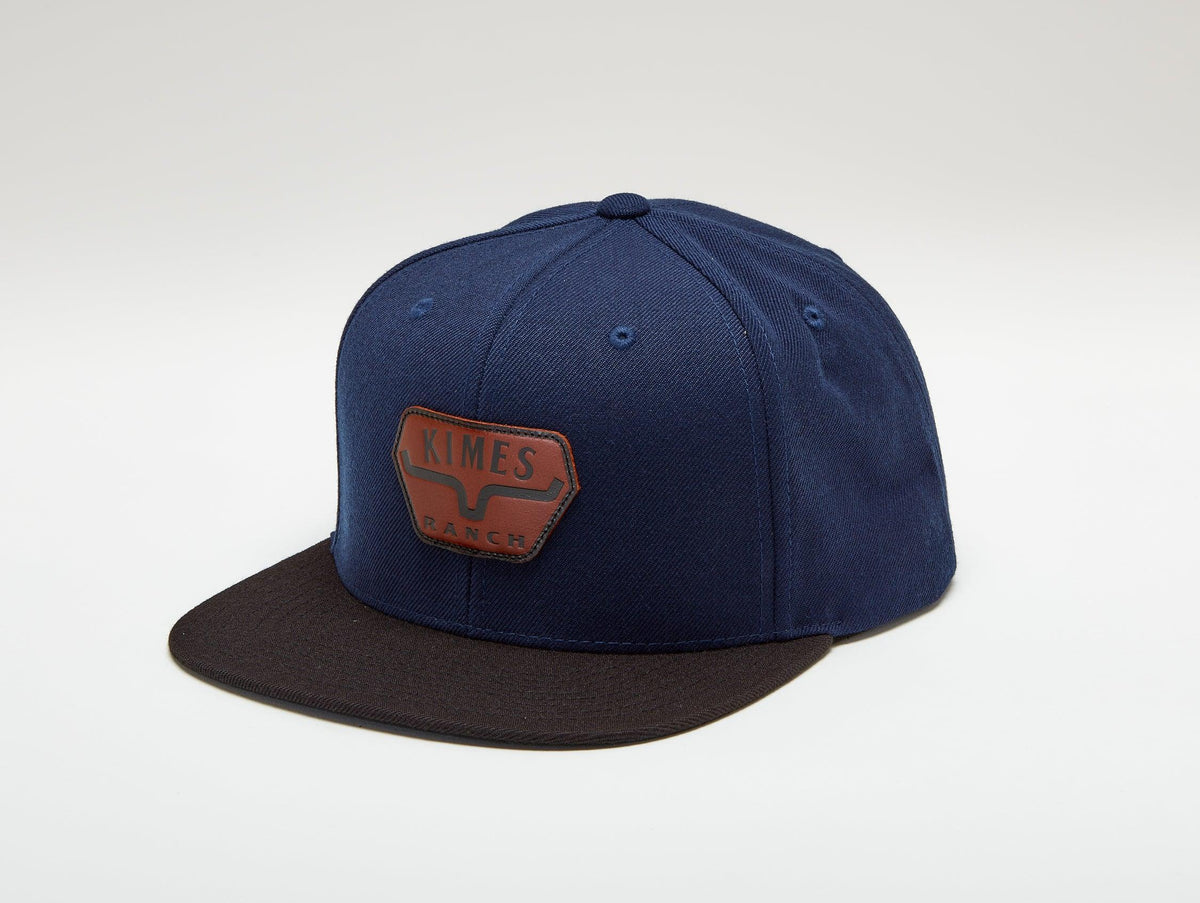 Kimes Ranch Premium Distance Hat in Navy, side view, with a brown logo patch on the front and a black brim