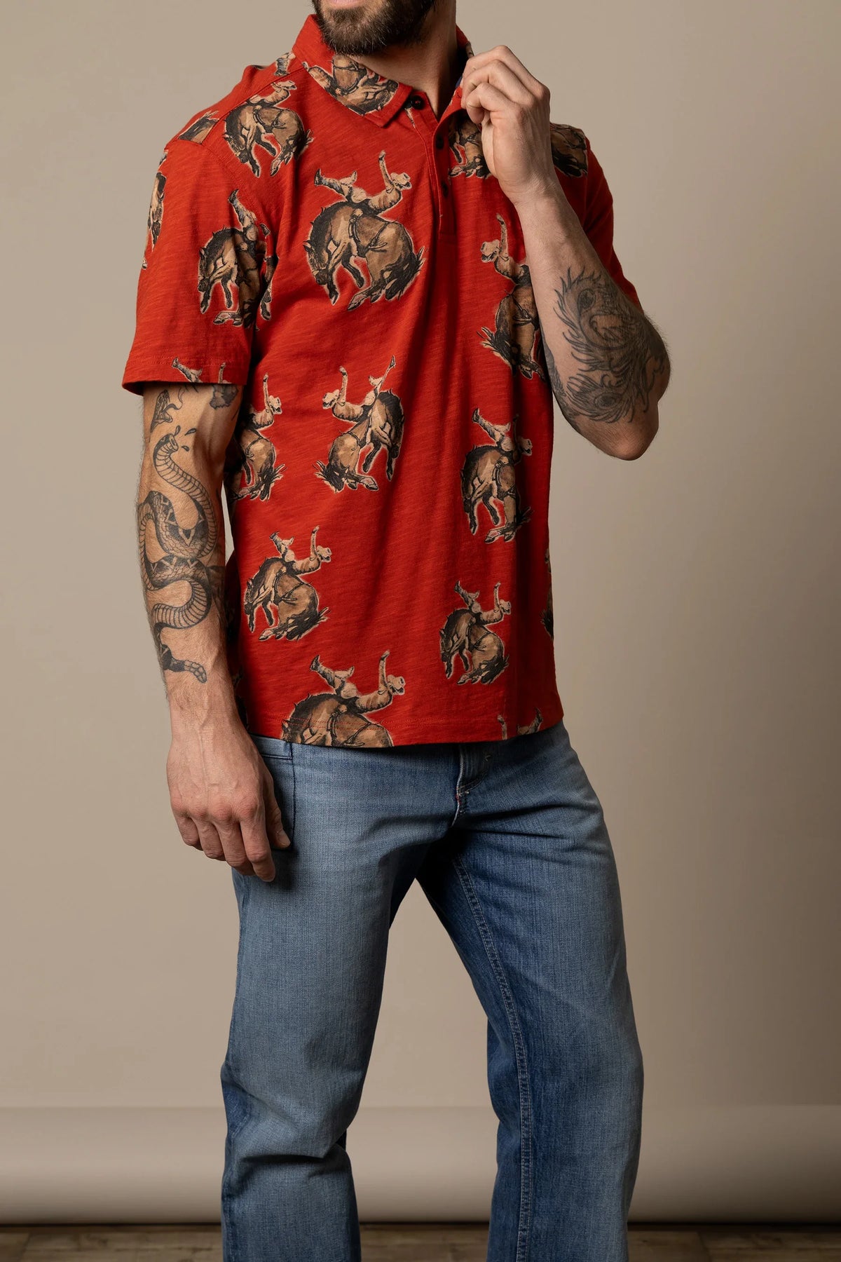 Kimes Ranch RP Winning Ride Polo in Brick Red with an all-over print of cowboys riding bucking broncos