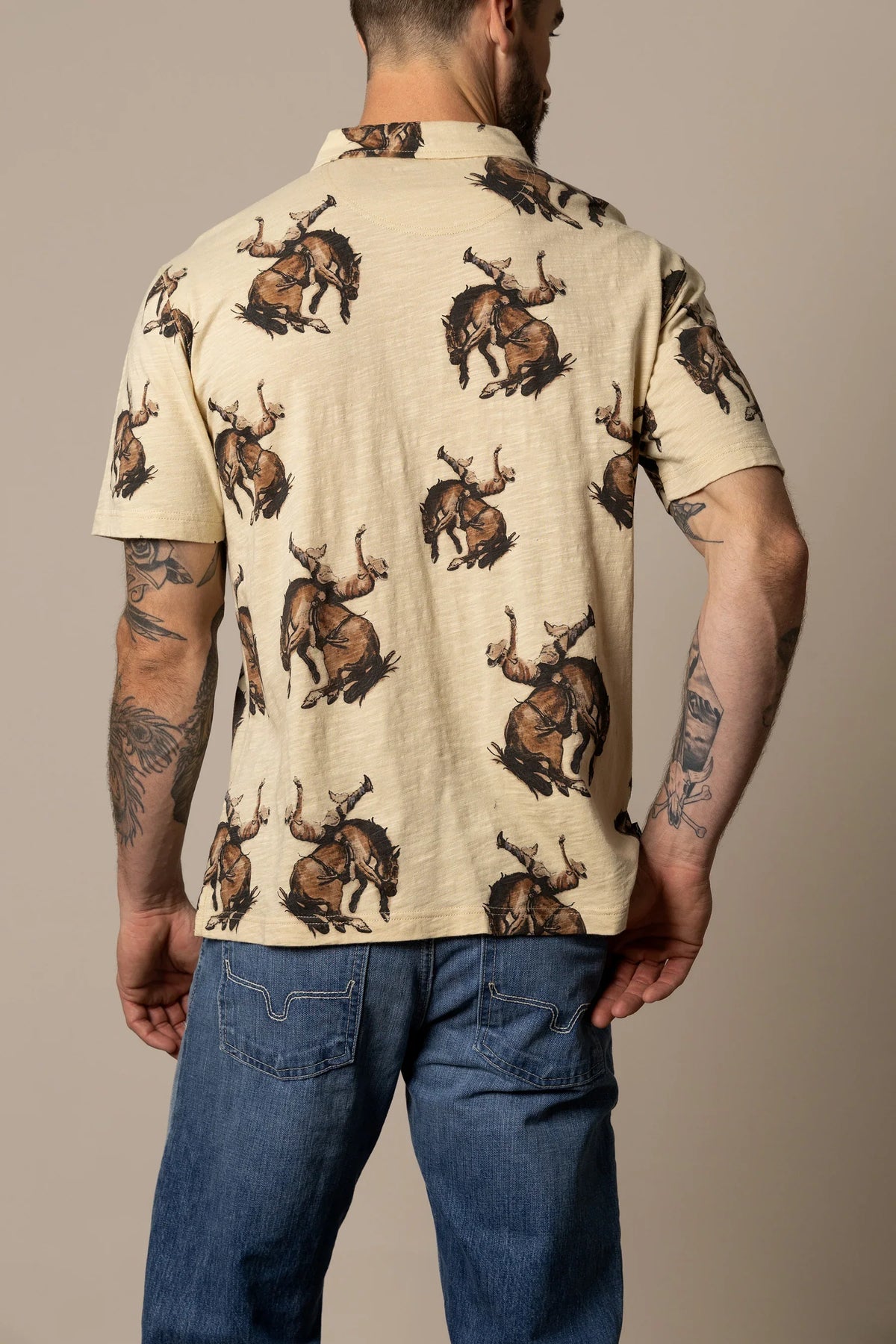 Kimes Ranch RP Winning Ride Polo in Tan, back view, with an all-over print of a cowboy riding a bucking bronco