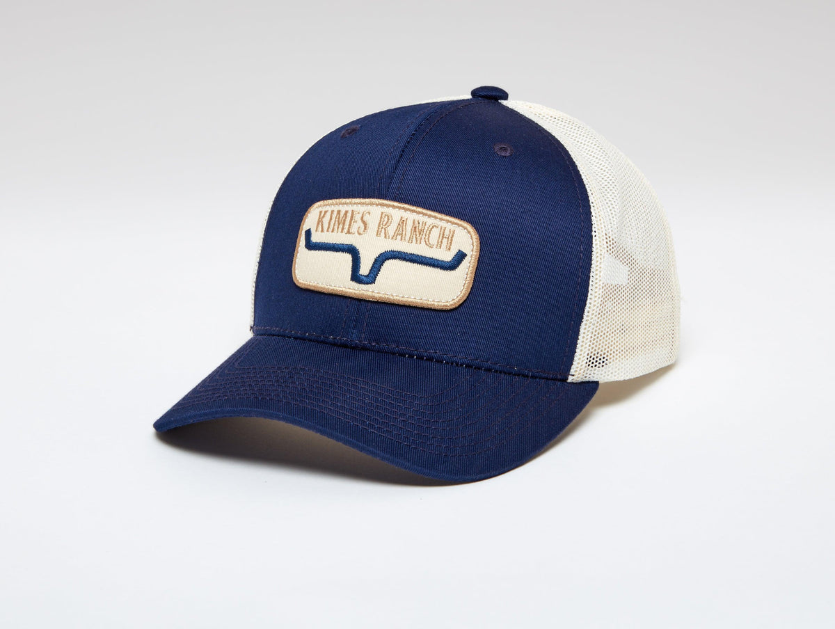 Kimes Ranch Rolling Trucker Hat in Carbon Blue, side view, with a front Kimes Ranch logo patch