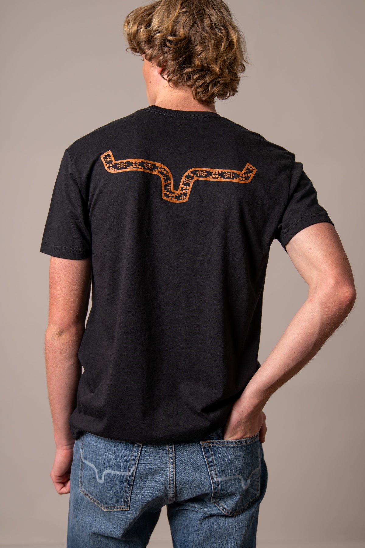 Kimes Ranch Rowell, back view, Black shirt with large orange and Black geometric steer horn graphic on the back