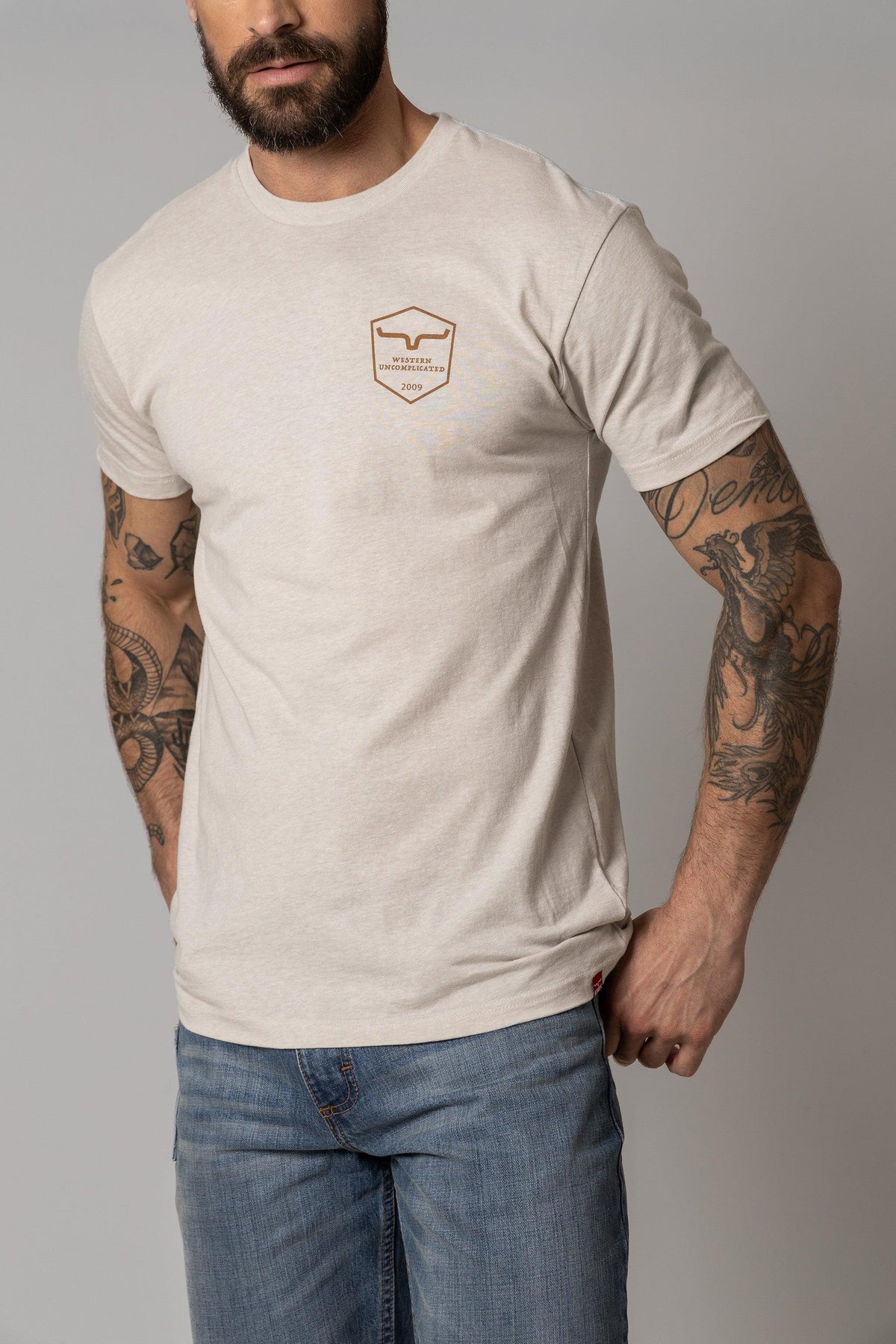 Kimes Ranch Shielded Trucker Shirt in Sand with a chest shield logo reading Western Uncomplicated 2009