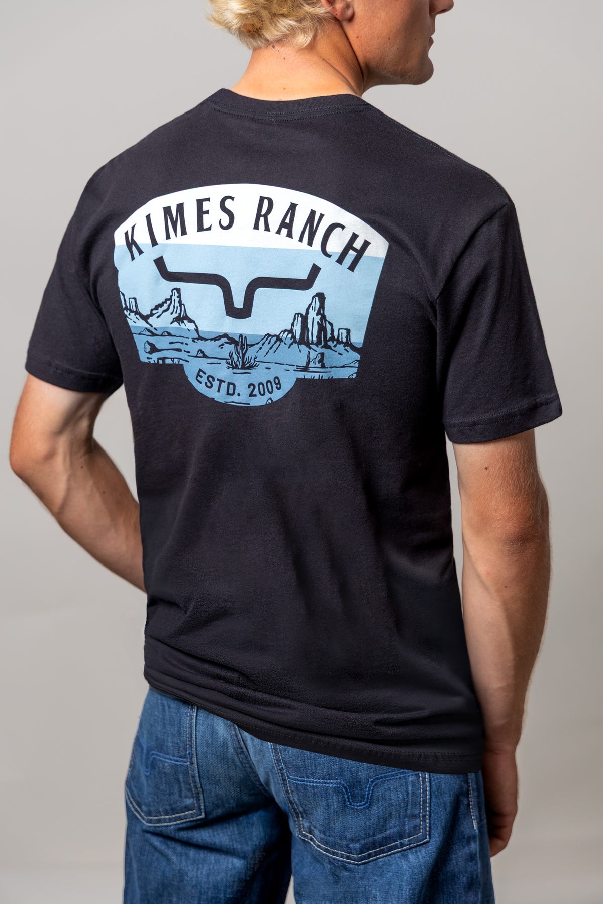 Kimes Ranch Southwestern shirt in Black, back view, with a back graphic of a desert landscape and the Kimes Ranch logo