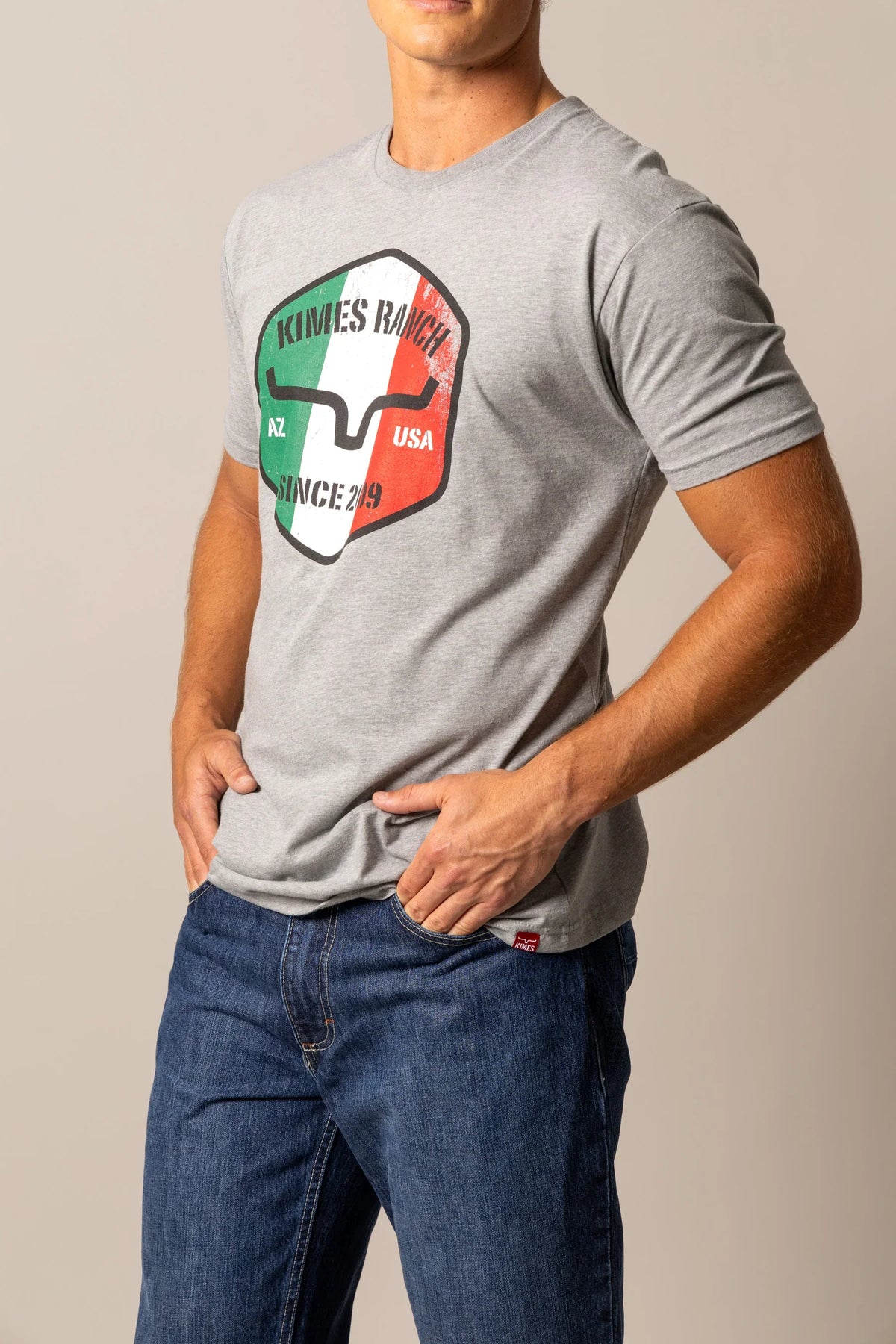 Kimes Ranch Triple Stripe shirt in Dark Grey Heather with a shield graphic featuring the Kimes Ranch logo
