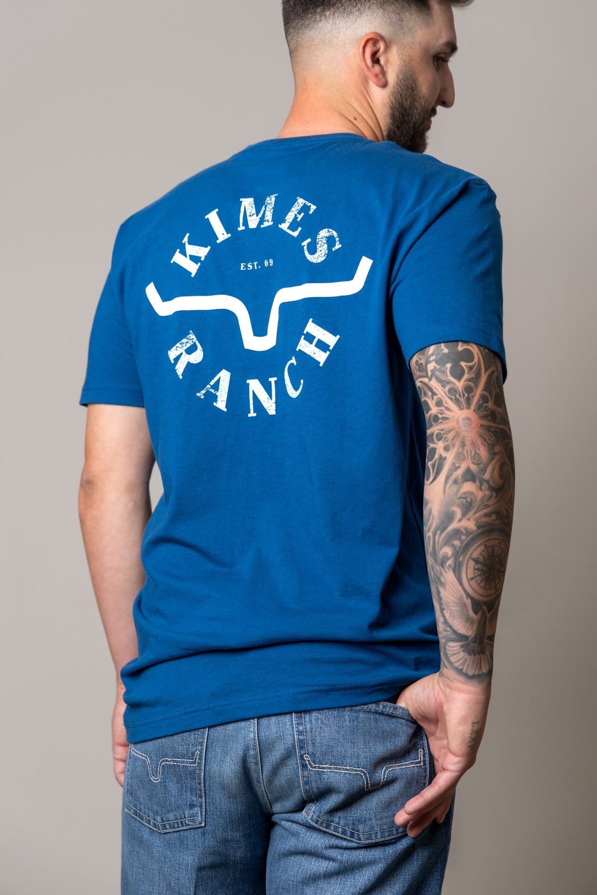 Kimes Ranch Uncomplicated shirt in Cool Blue, back view, with a large back graphic featuring the Kimes Ranch logo