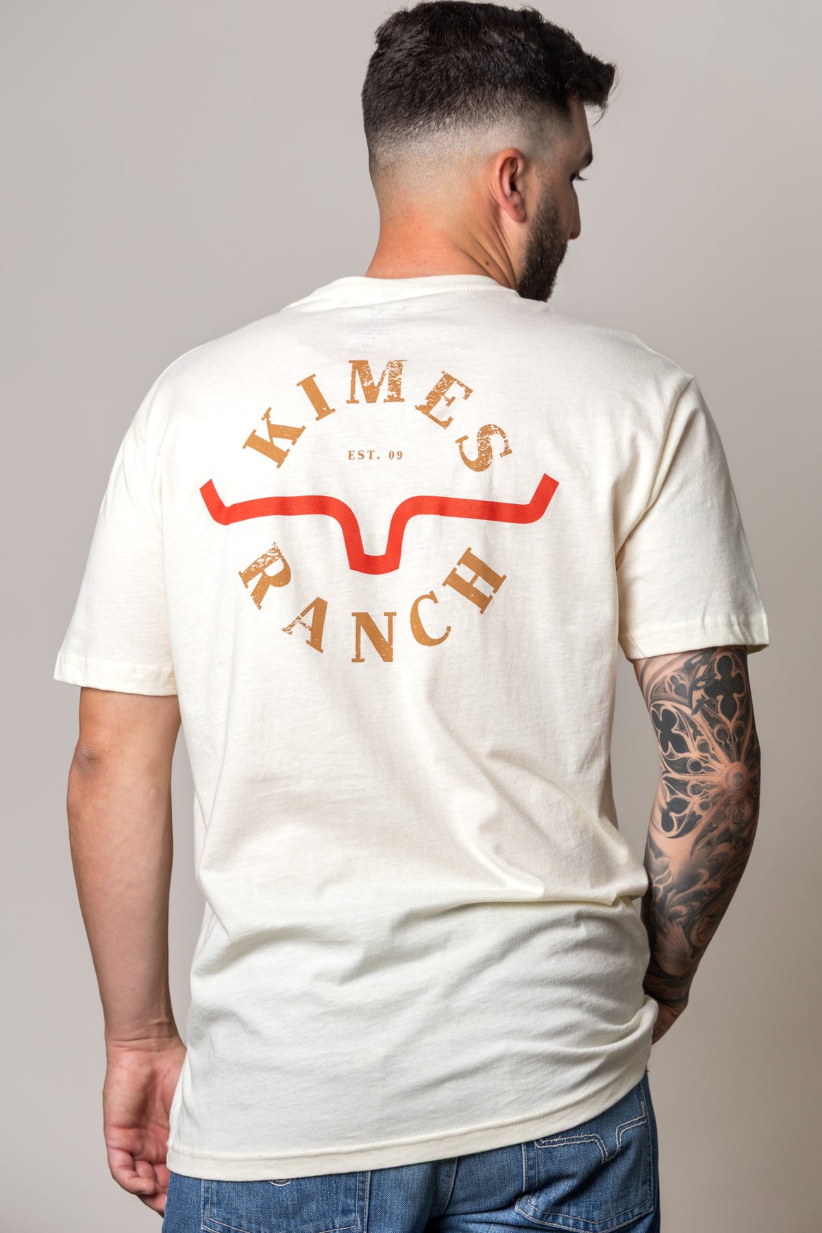 Kimes Ranch Uncomplicated shirt in Natural, back view, with a back graphic of the Kimes Ranch logo and EST. 09 text