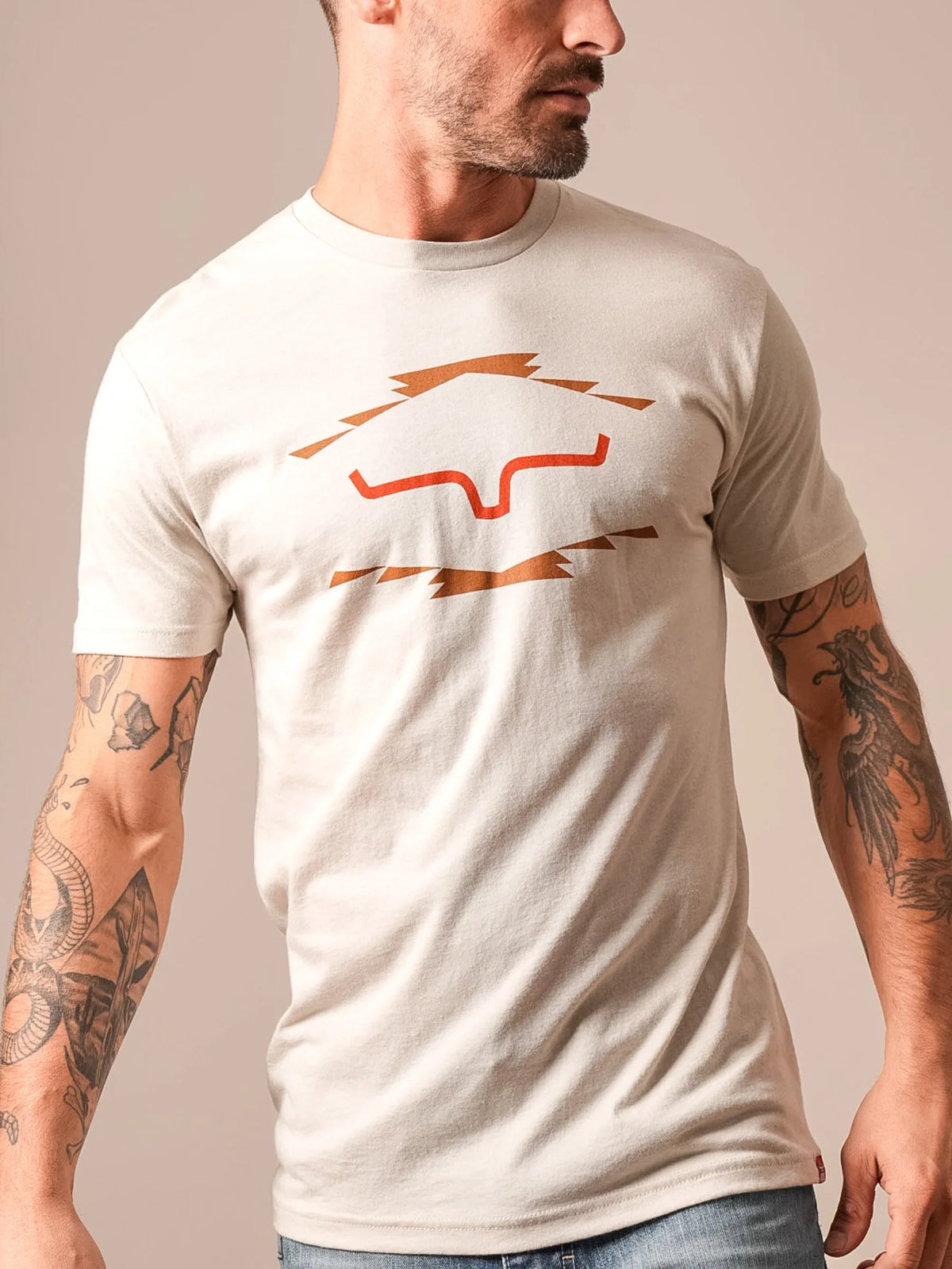 Kimes Ranch Vintage Badge shirt in Sand with a graphic of a stylized Kimes Ranch logo in orange and brown