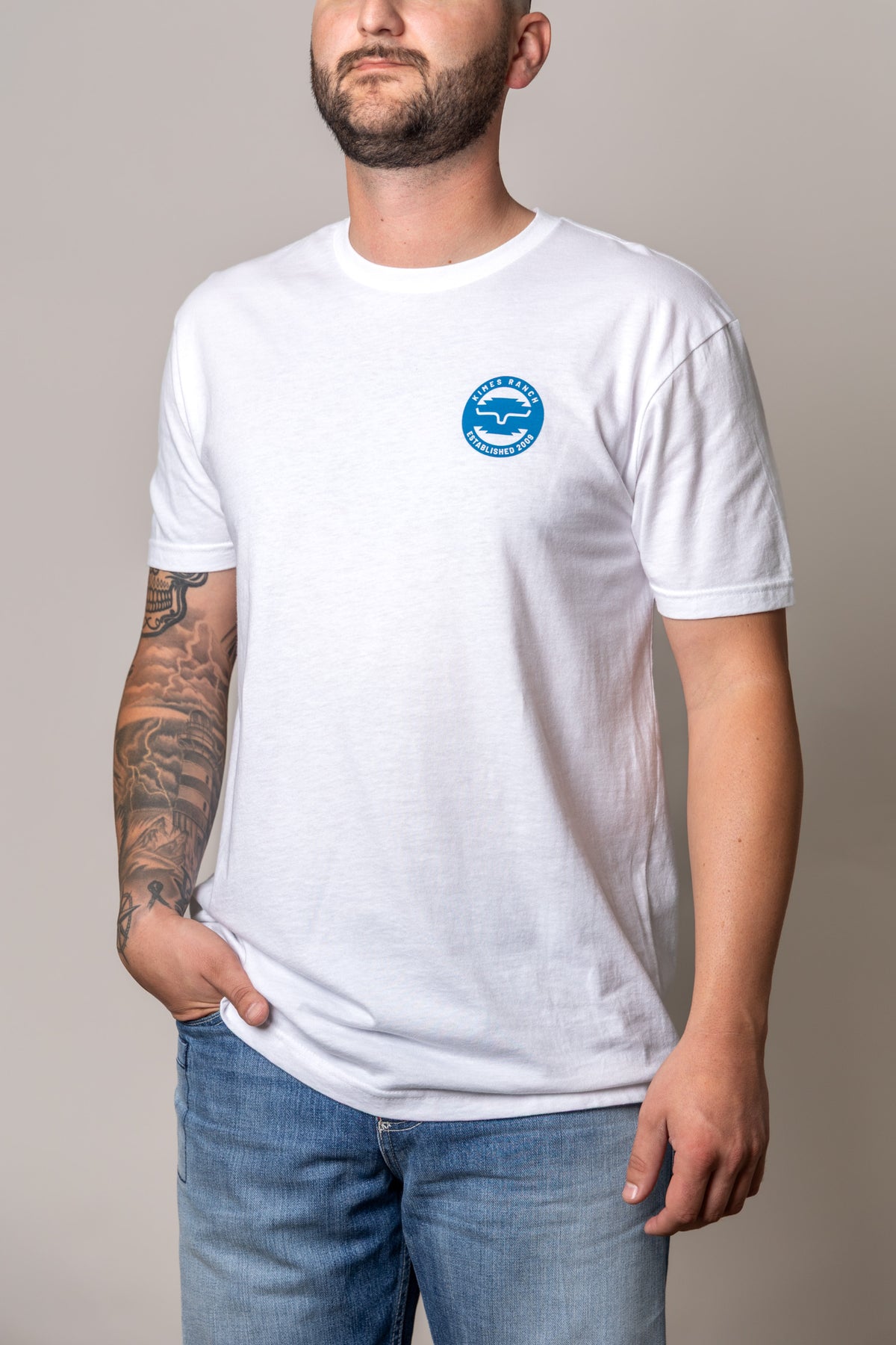 Kimes Ranch Wood Stamp White short sleeve shirt with a blue circular logo on the chest