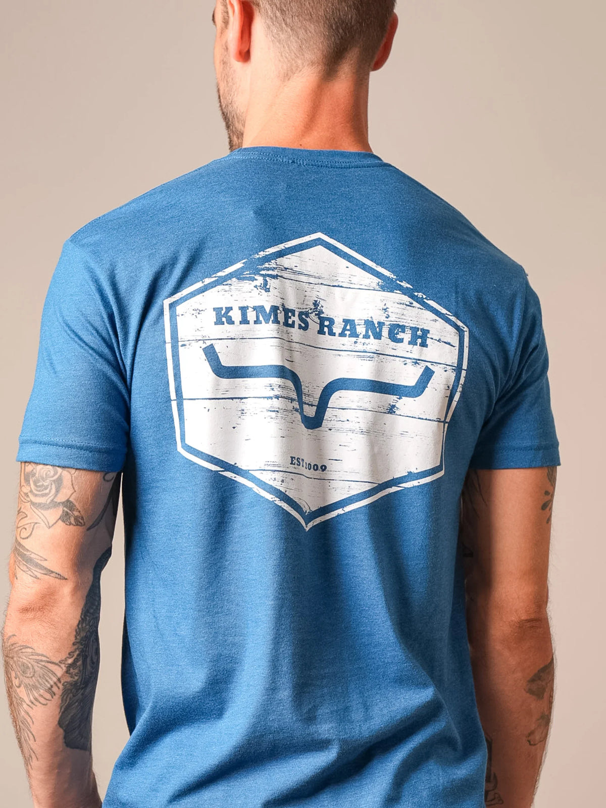 Kimes Ranch Wooden Hex shirt in Heather Cool Blue, back view, with large back graphic featuring the Kimes Ranch logo
