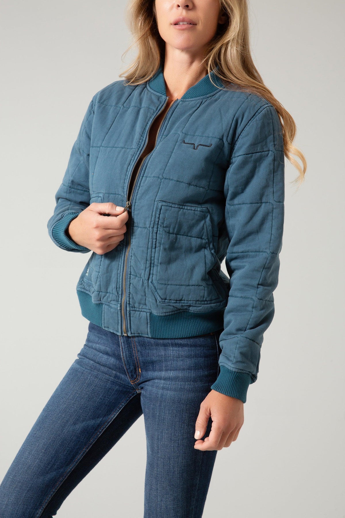 Kimes Ranch Bronc Bomber Jacket in Dark Blue, side view, with quilted stitching, front pockets, and logo