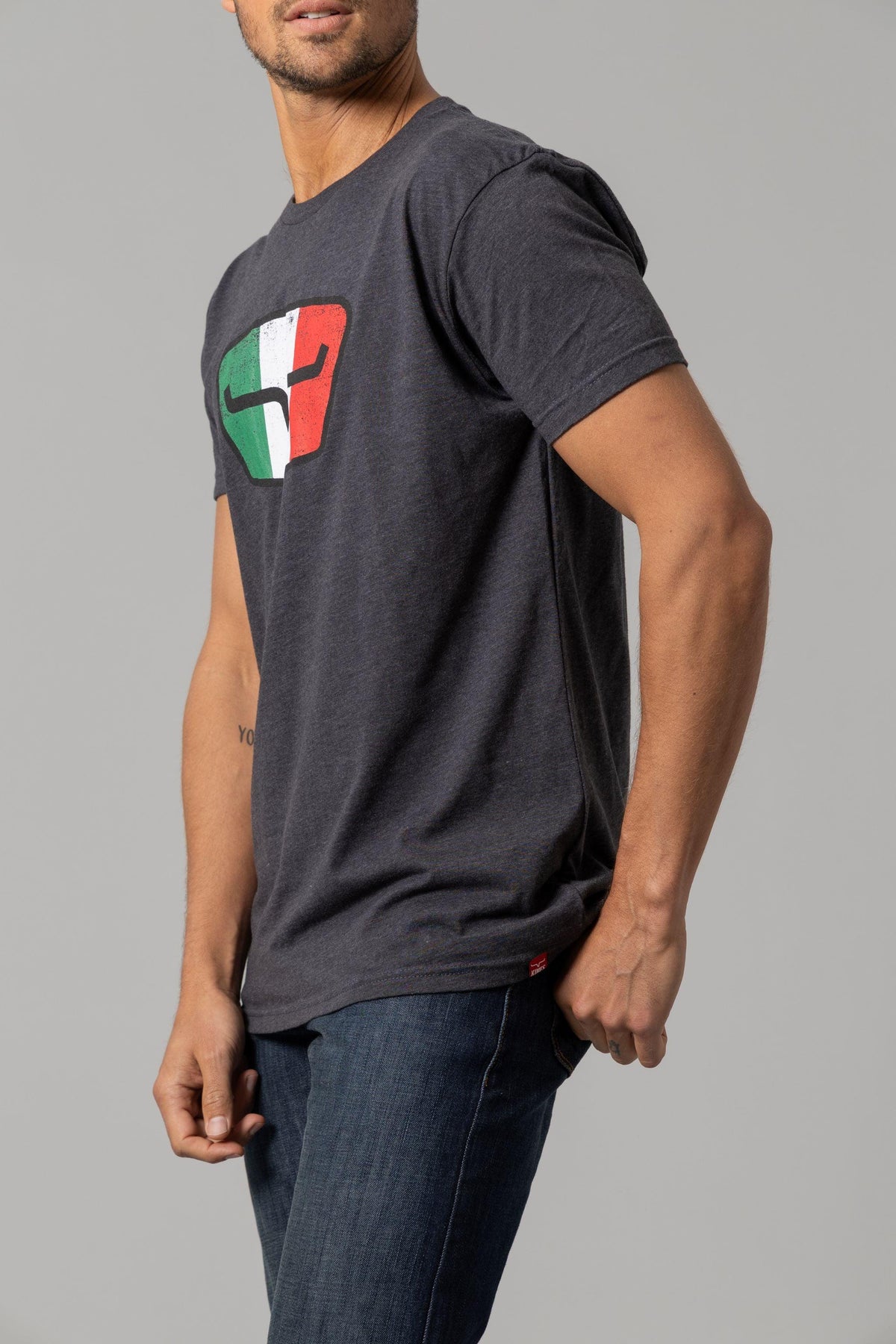 Kimes Ranch Tri-Color Tee in Charcoal, side view, with a distressed shield graphic in green, white, and red