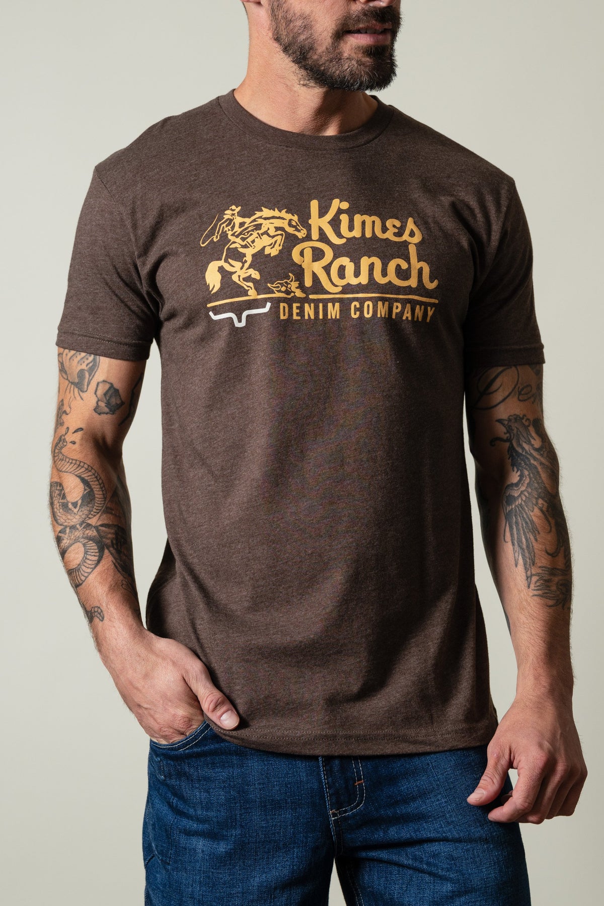 Kimes Ranch Davona Dale Espresso short sleeve shirt with graphic of cowboy on bucking horse and "Kimes Ranch DENIM COMPANY"