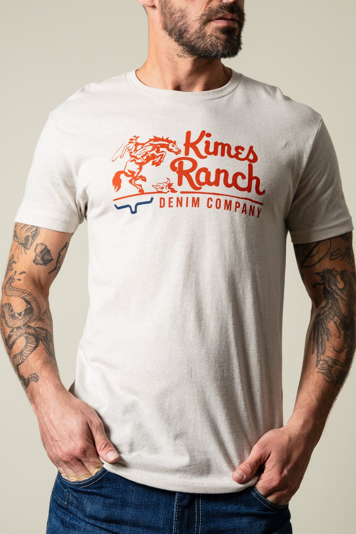 Kimes Ranch Davona Dale Sand short sleeve tee with orange horse rider graphic and 'Kimes Ranch DENIM COMPANY' text